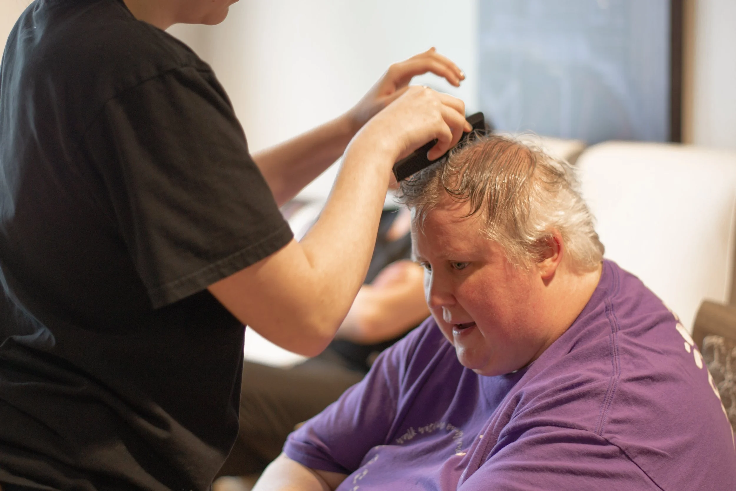 A person with curly blonde hair getting their hair cut or styled by a hairstylist.