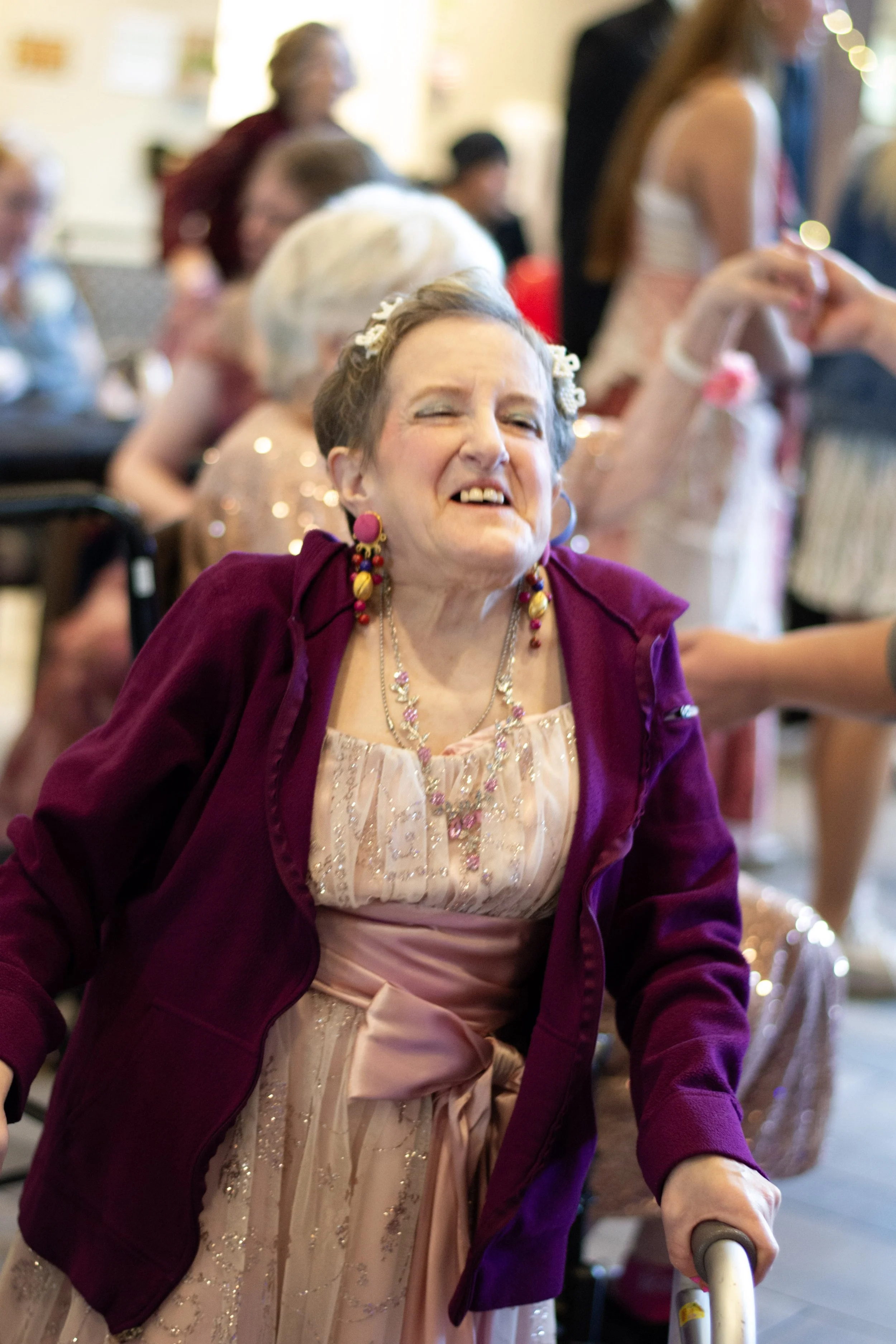 Woman smiling and enjoying herself at a social gathering, surrounded by other people in a festive atmosphere.