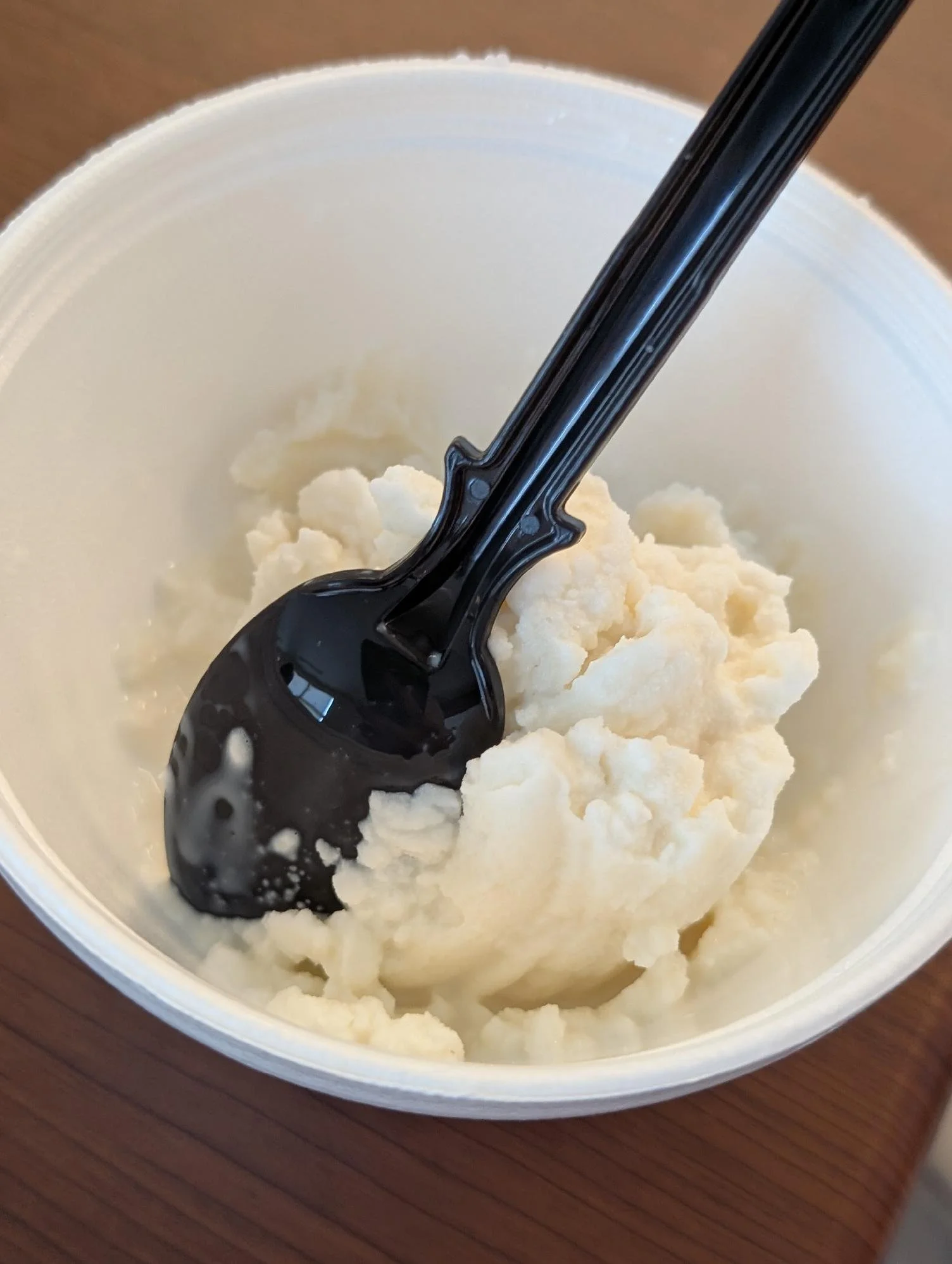 A container of vanilla ice cream with a black spoon inserted into it.