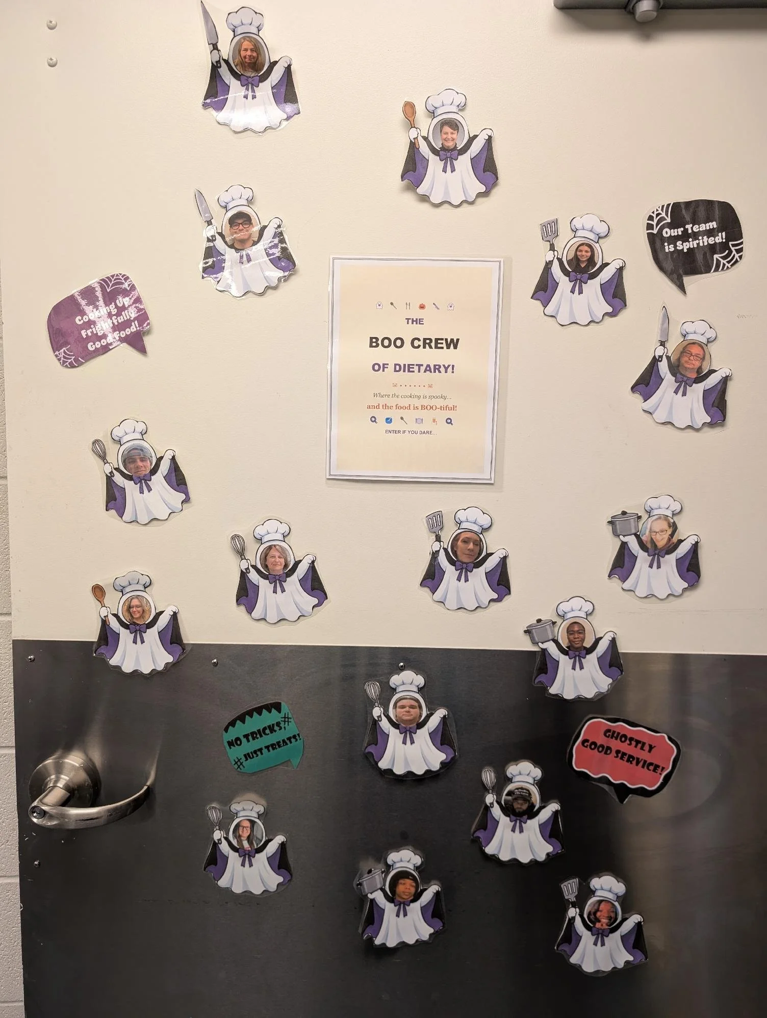 A wall display with paper cutouts of chefs with photos of people's faces, dressed in white chef uniforms with purple accents, holding kitchen utensils. Some cutouts are in speech bubbles with humorous messages such as 'Cooking up a frightful full of 