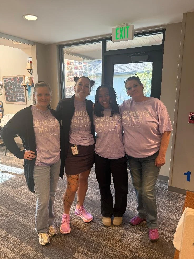 Four women standing inside a building, smiling at the camera, wearing matching pink T-shirts with the message 'More Matters'.