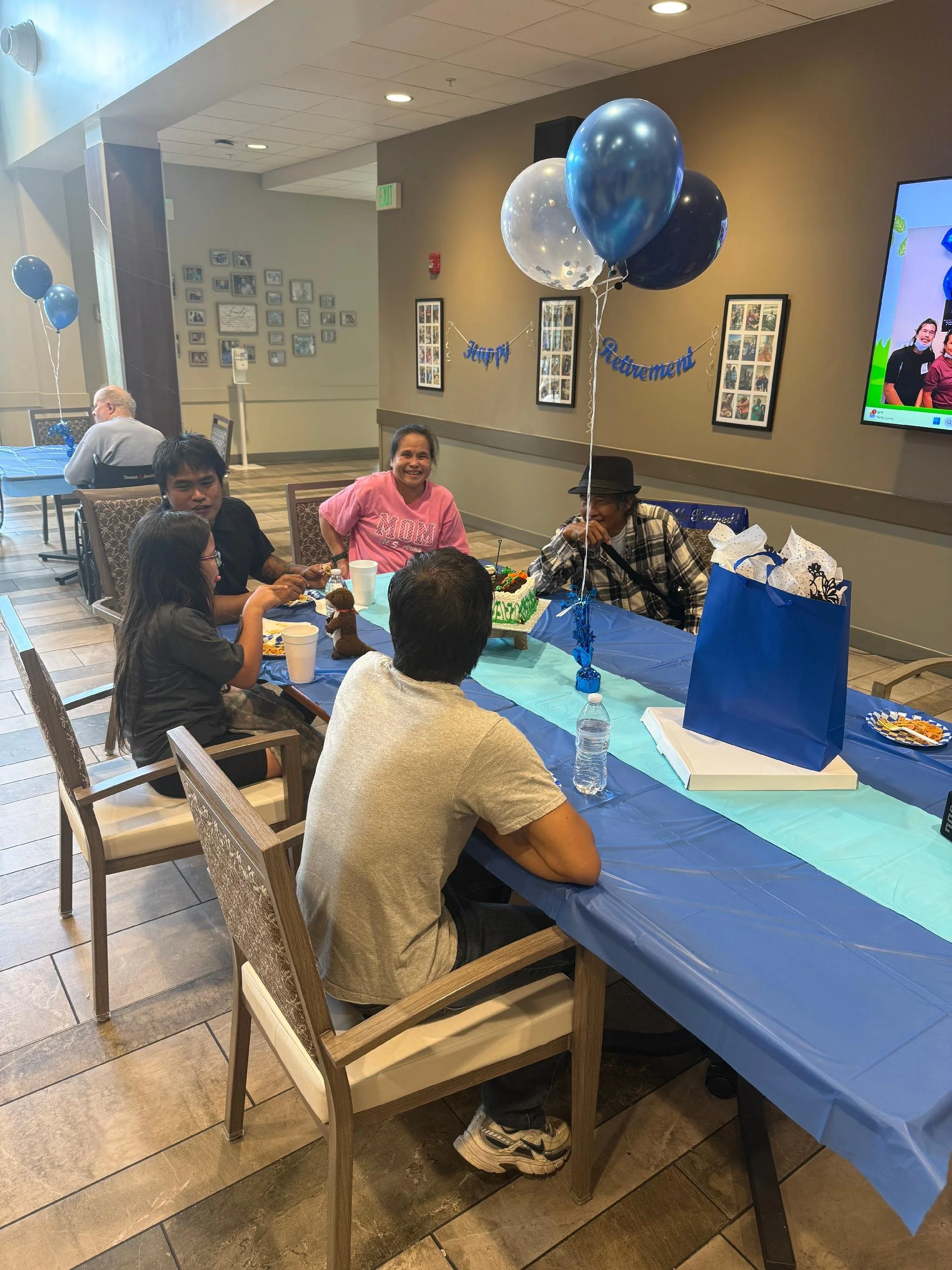 People celebrating at a birthday party with balloons, cake, and decorations in a decorated room.