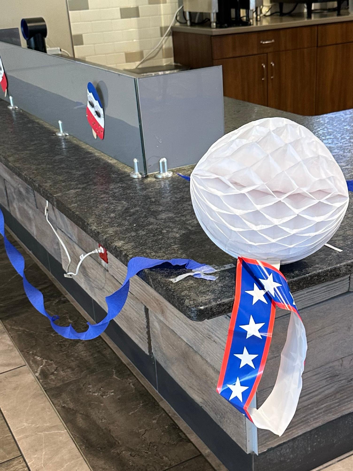 A table decorated with patriotic Christmas decorations, including a star and flag-themed ribbons, and a white paper lantern.