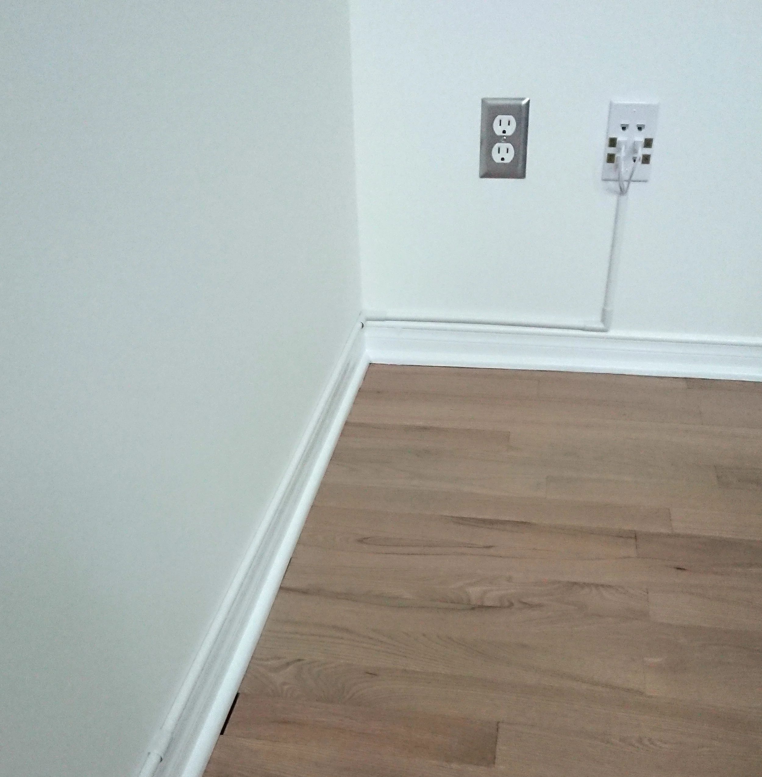 Close-up of a wall with electrical outlets and cable conduit.
