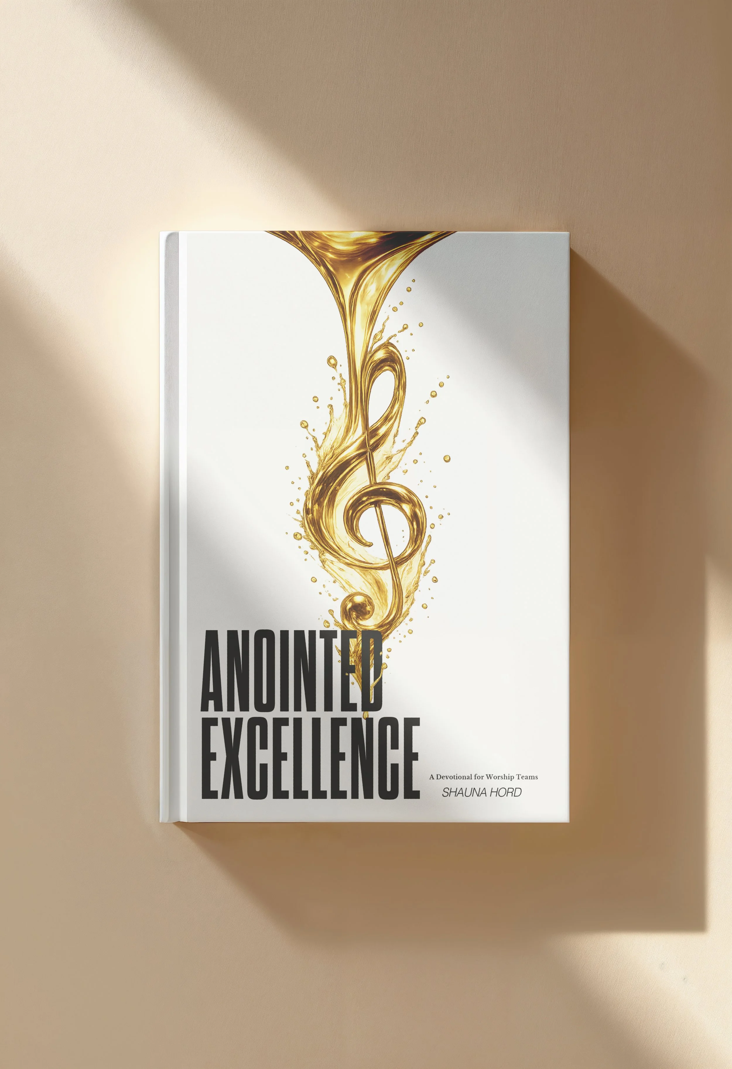 Book titled "Anointed Excellence" with a cover design featuring a golden musical treble clef with fluid, swirling patterns, and small golden droplets on a white background.