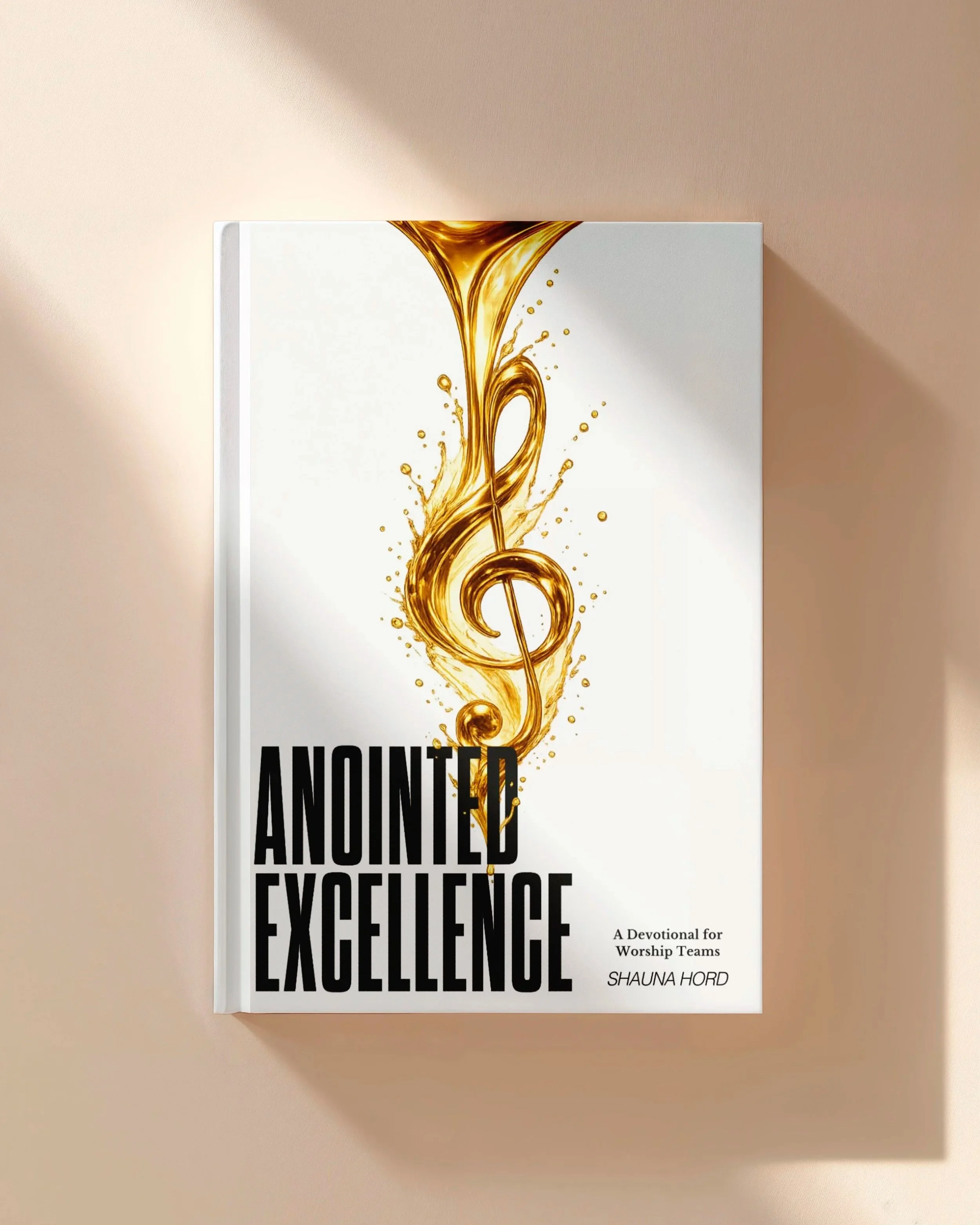 Book cover with a white background and a golden musical note design. The title reads "Anointed excellence" in large black letters. Subtitle says "A devotional for worship teams," and the author's name is Shauna Hord.