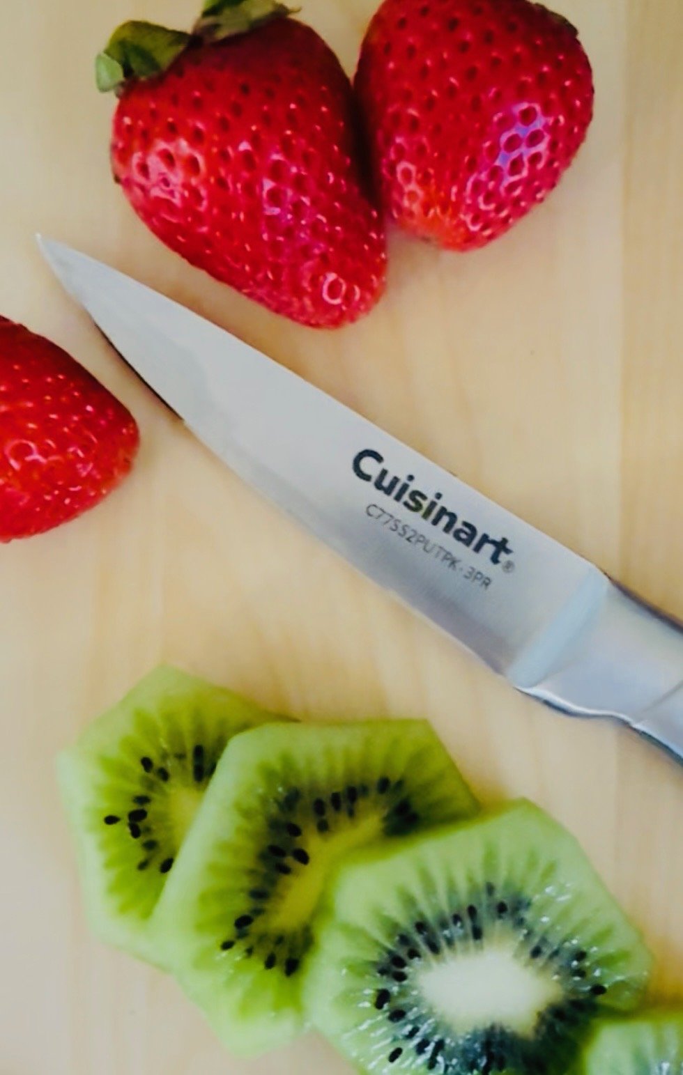 Close-up of strawberries and kiwi slices on a cutting board with a Cuisinart knife.