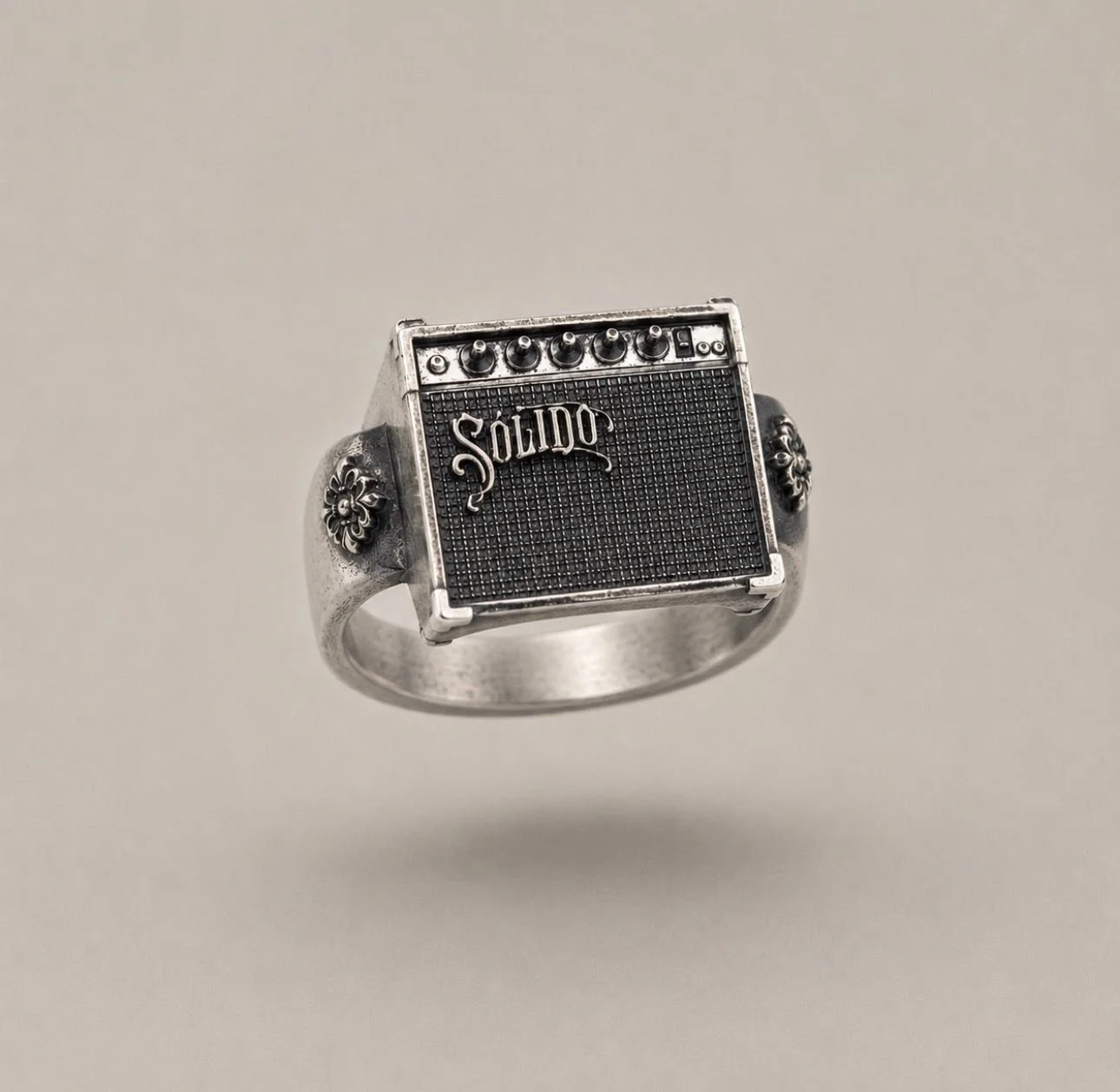 Anillo de plata con diseño de un amplificador de guitarra vintage en miniatura, con el nombre de la marca “Solido” grabado en la parte frontal.