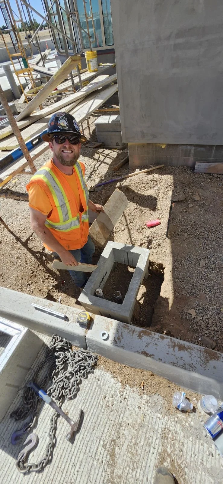 Construction worker in safety vest and helmet standing at a construction site.