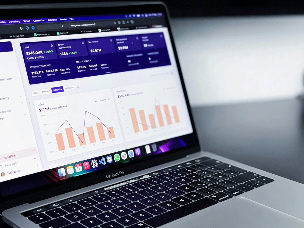 Laptop computer displaying business analytics and sales data charts with app icons on dock.