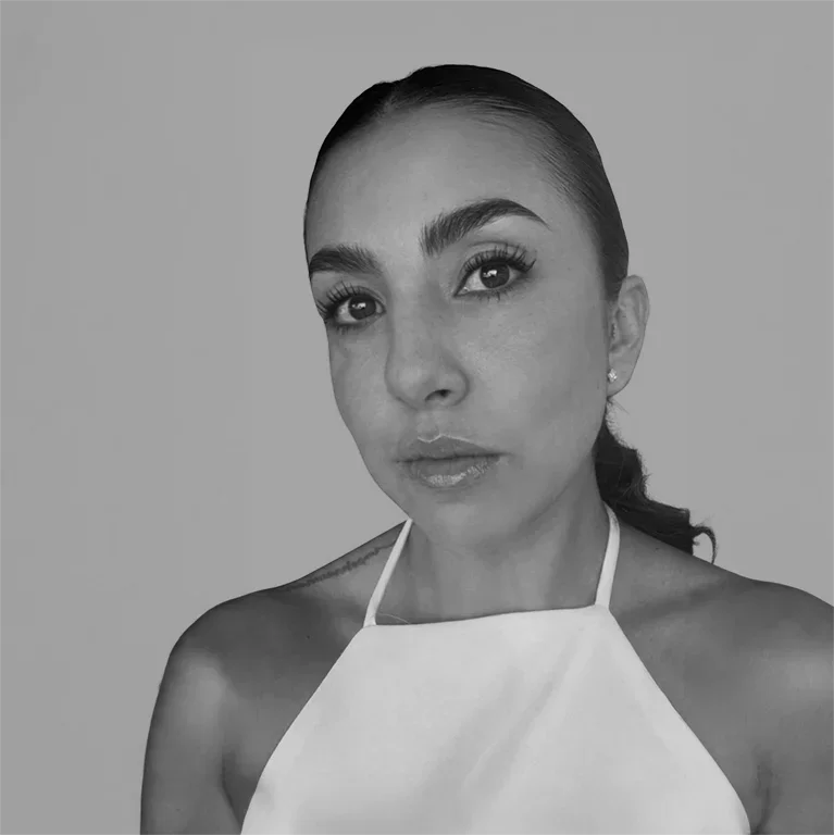 Black and white portrait of a woman with styled hair, makeup, and earrings, wearing a halter top or dress.