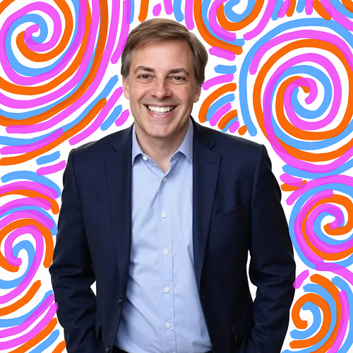 A smiling man in a dark suit and light blue shirt standing in front of a colorful, swirling background.