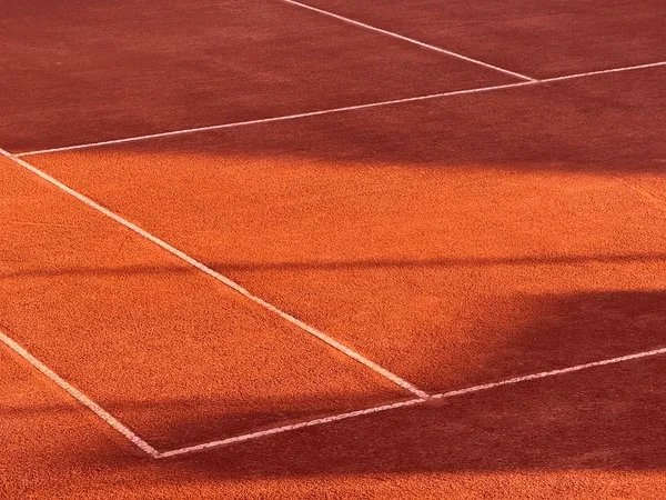 Close-up of a clay tennis court surface with white boundary lines.