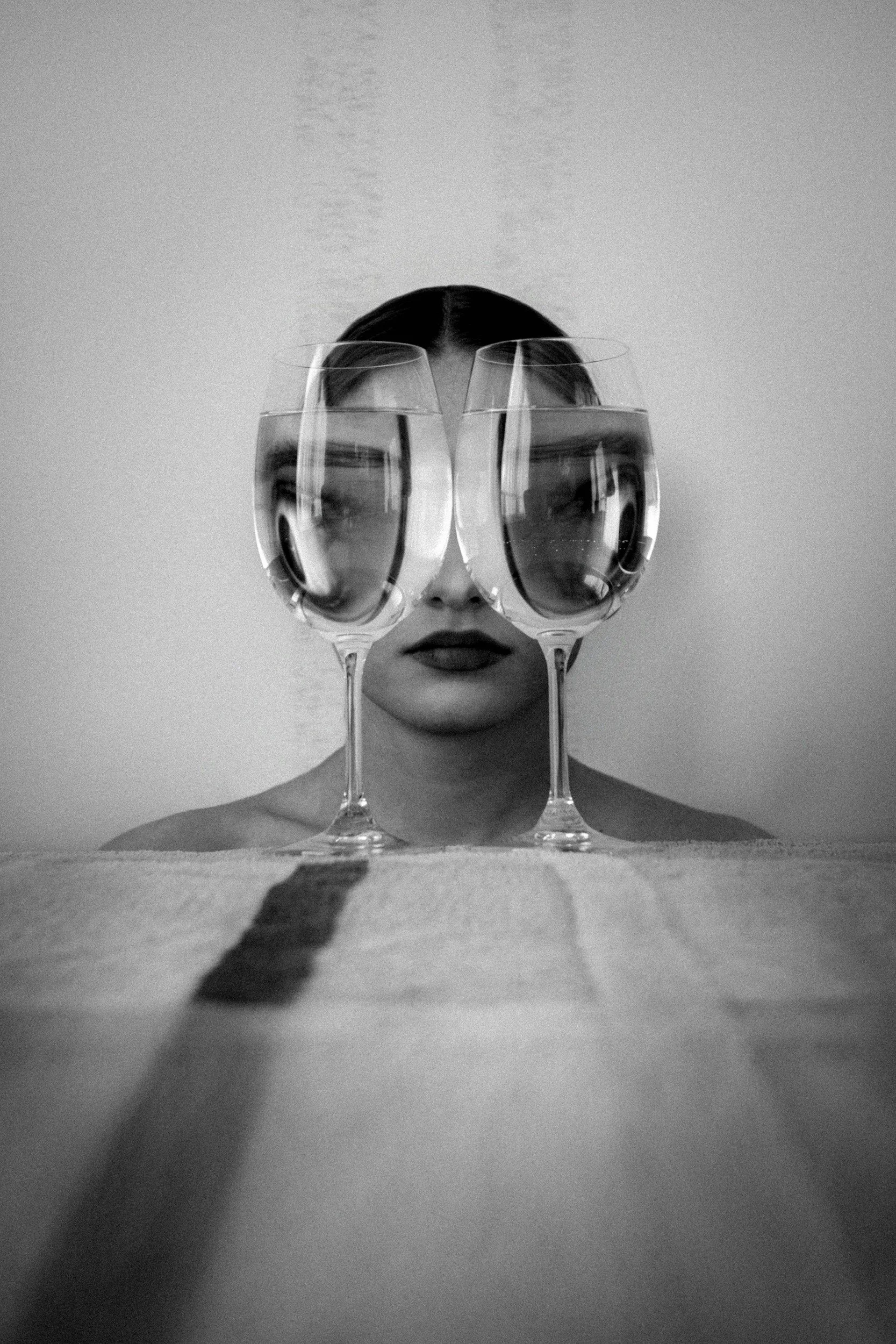 Person peering through wine glasses held up to their eyes like a looking glass
