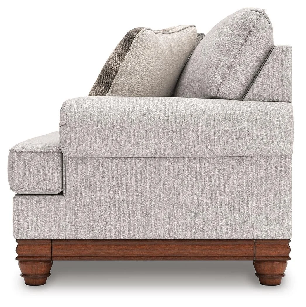 Farmhouse-inspired sofa with soft neutral upholstery, reversible cushions, decorative turned legs, and coordinating plaid accent pillows.