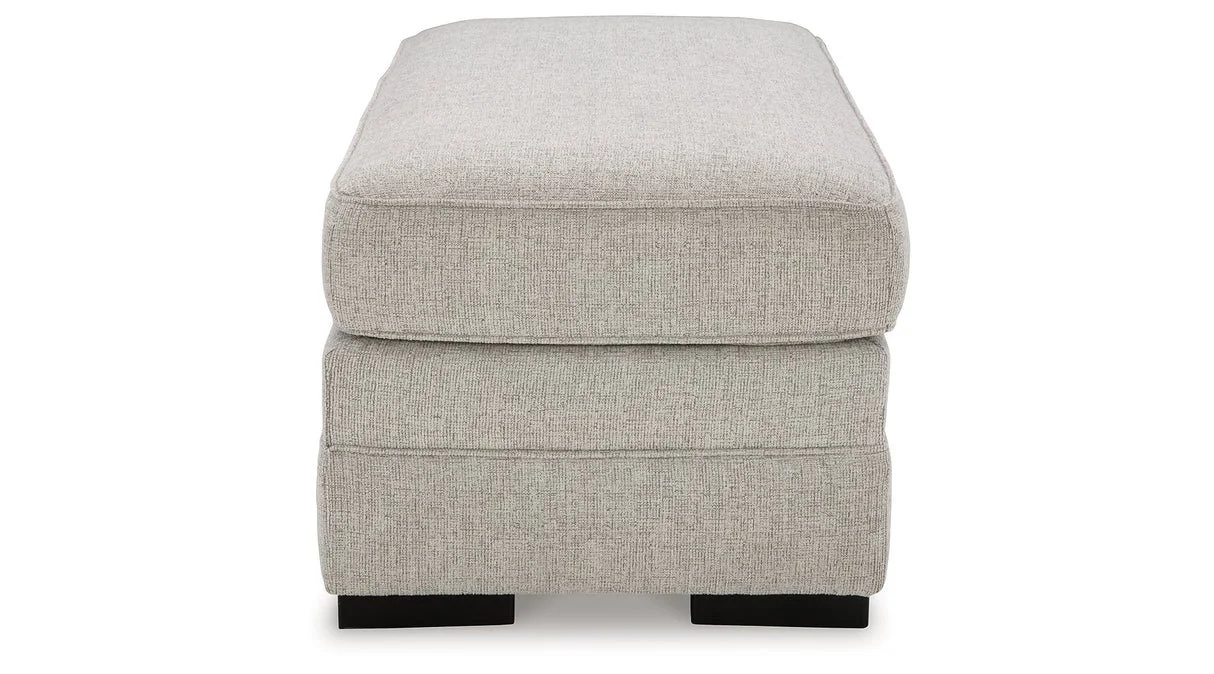 Matching upholstered ottoman with textured polyester fabric, firm foam cushioning, and faux wood feet.