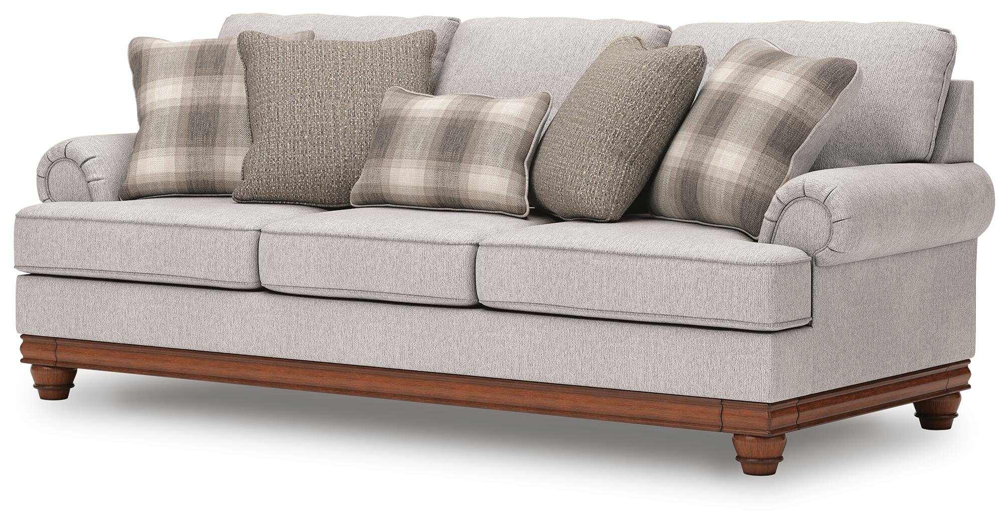 Farmhouse-inspired sofa with soft neutral upholstery, reversible cushions, decorative turned legs, and coordinating plaid accent pillows.