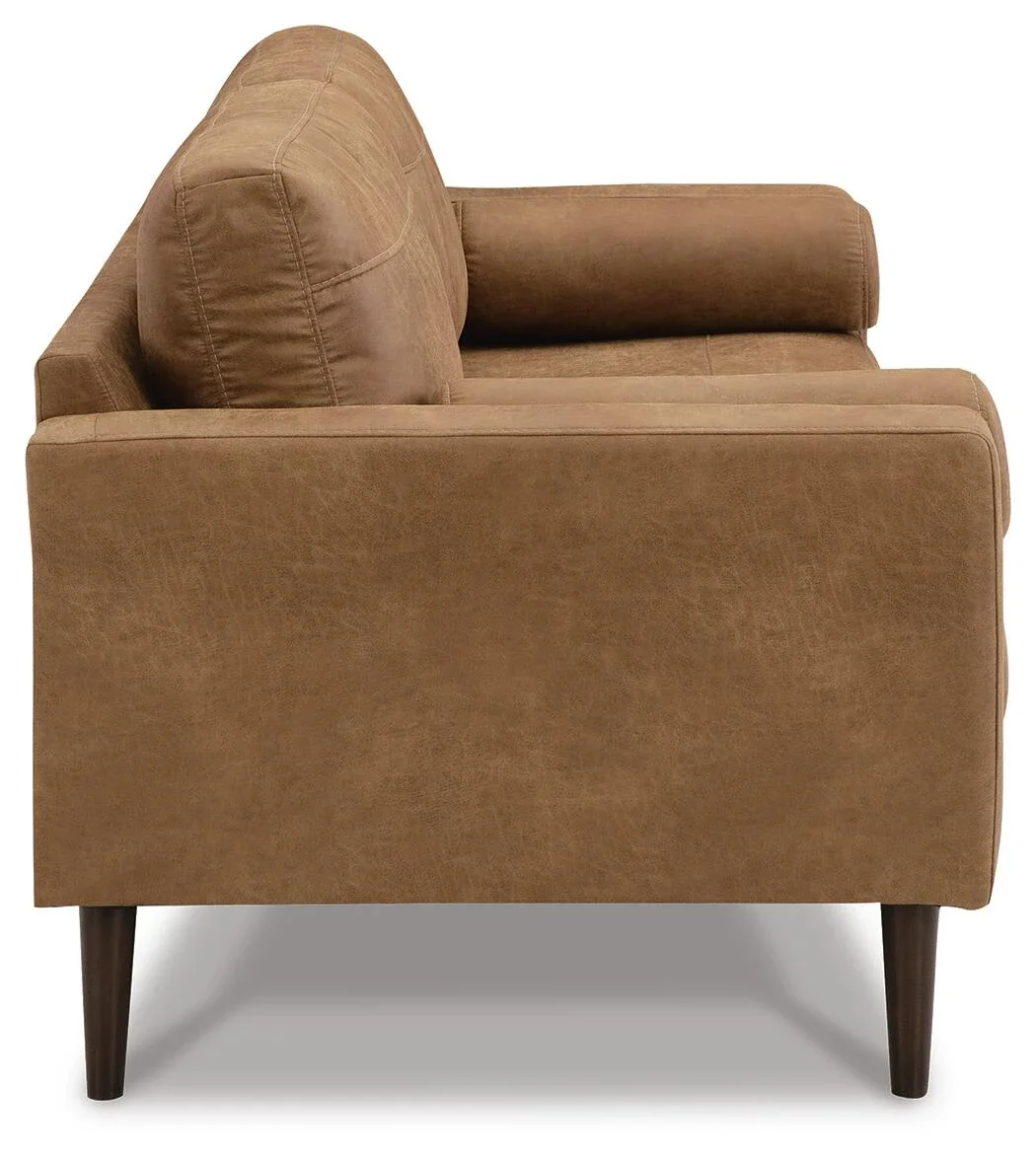 Modern sofa with warm caramel faux leather upholstery, plush loose cushions, bolster pillows, and faux wood accent legs.