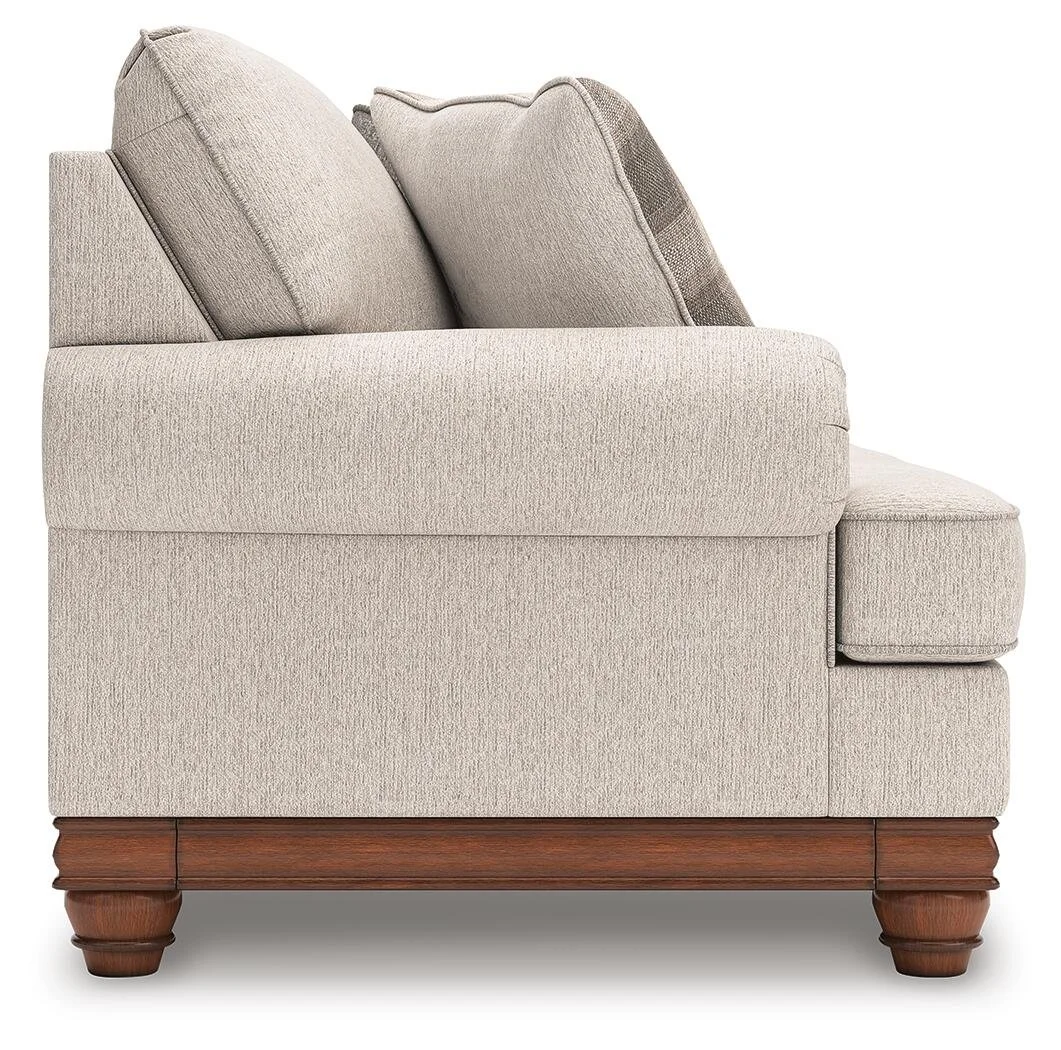 Farmhouse-inspired sofa with soft neutral upholstery, reversible cushions, decorative turned legs, and coordinating plaid accent pillows.