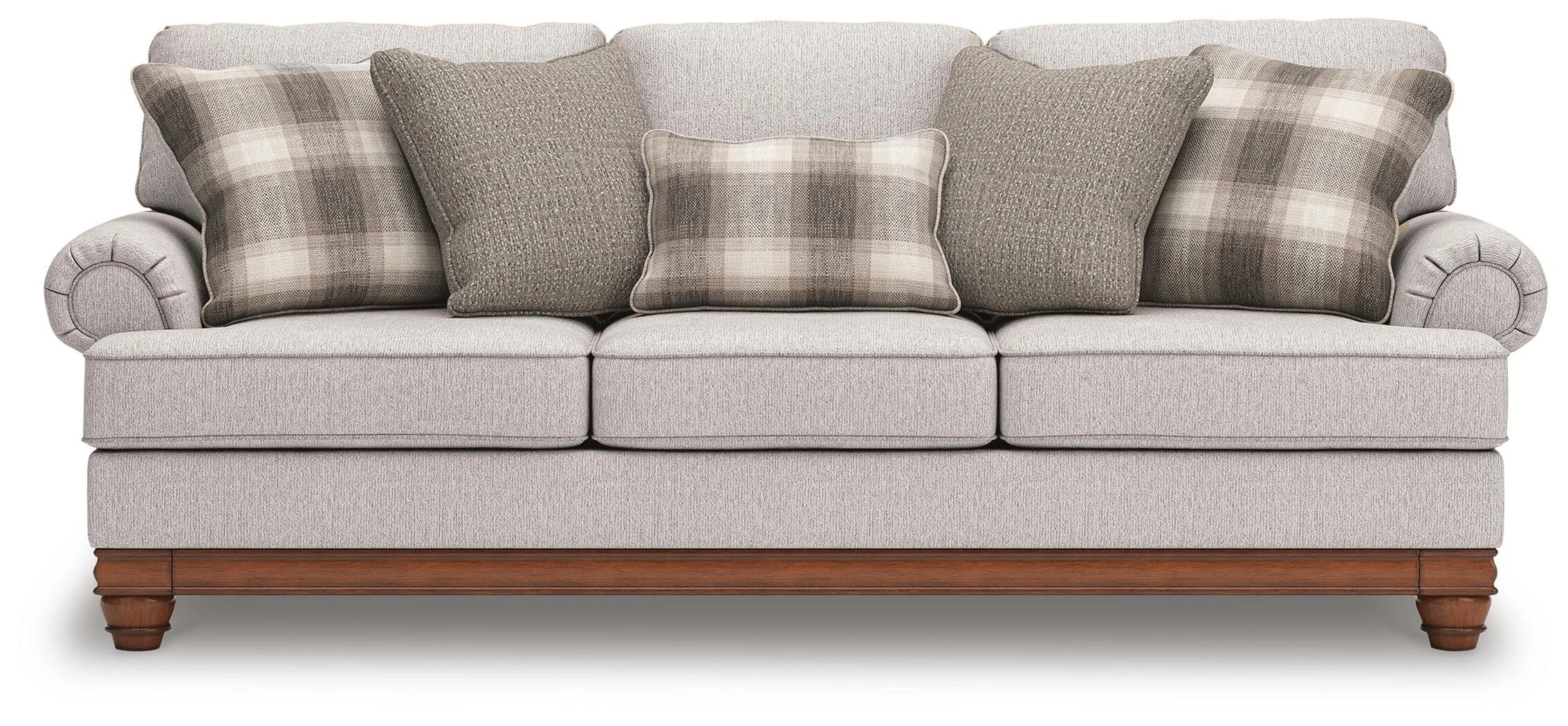 Farmhouse-inspired sofa with soft neutral upholstery, reversible cushions, decorative turned legs, and coordinating plaid accent pillows.