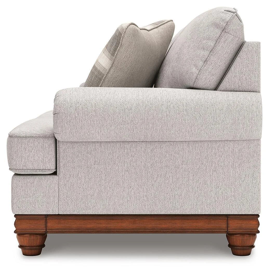 Matching farmhouse loveseat with soft neutral upholstery, reversible cushions, decorative turned legs, and coordinating accent pillows.