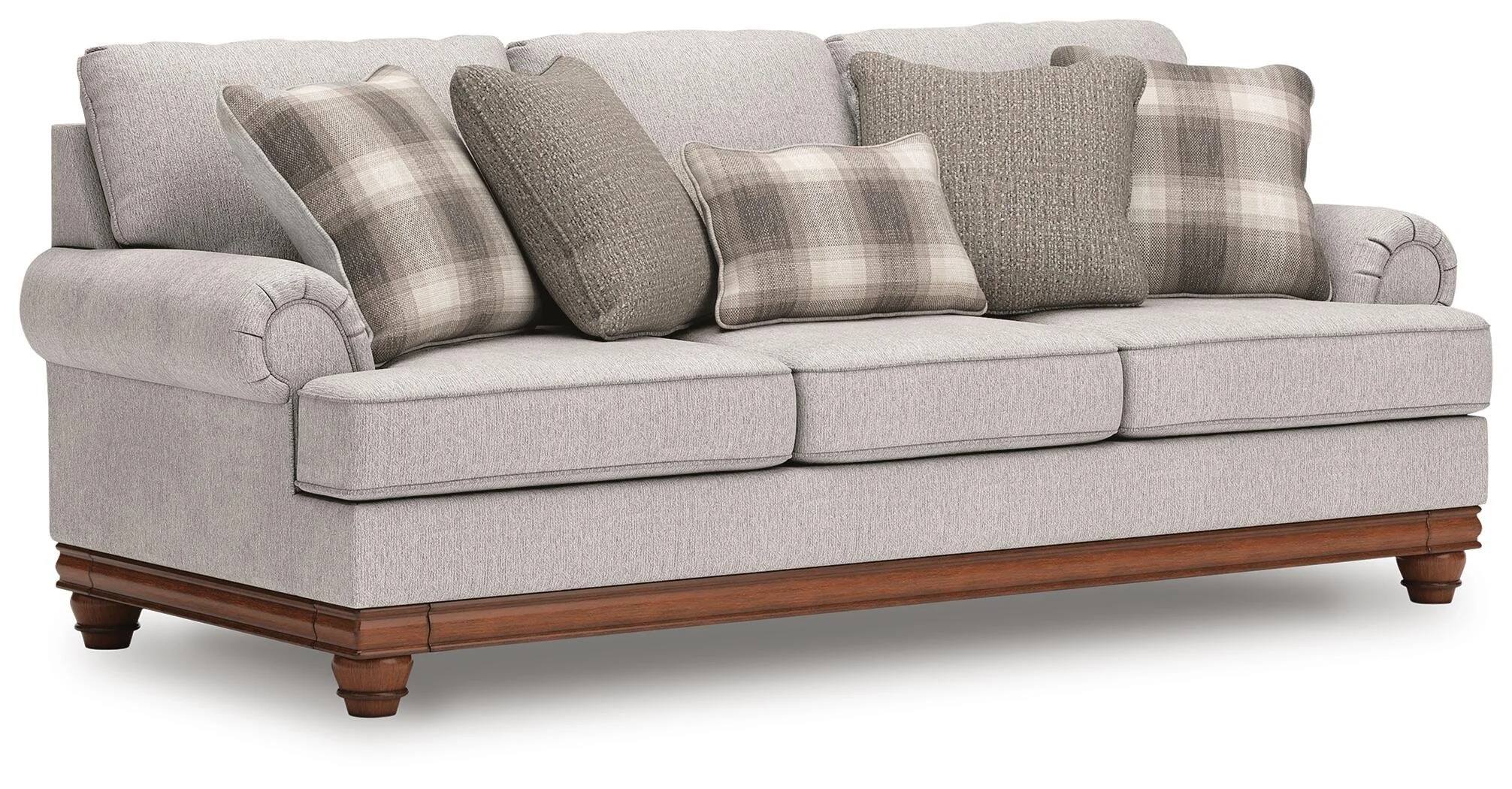Farmhouse-inspired sofa with soft neutral upholstery, reversible cushions, decorative turned legs, and coordinating plaid accent pillows.