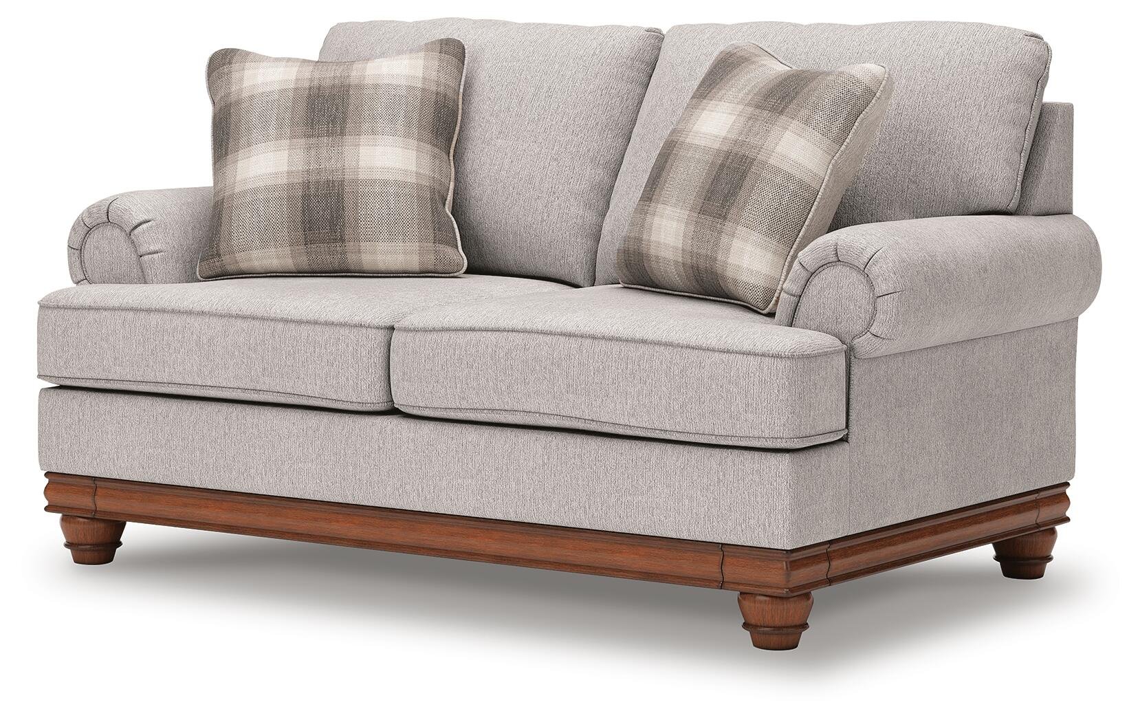 Matching farmhouse loveseat with soft neutral upholstery, reversible cushions, decorative turned legs, and coordinating accent pillows.