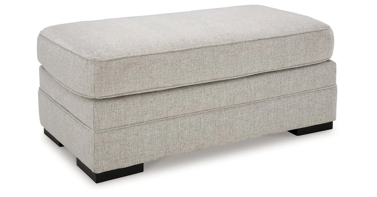 Matching upholstered ottoman with textured polyester fabric, firm foam cushioning, and faux wood feet.