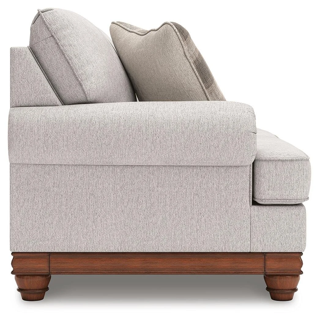 Matching farmhouse loveseat with soft neutral upholstery, reversible cushions, decorative turned legs, and coordinating accent pillows.