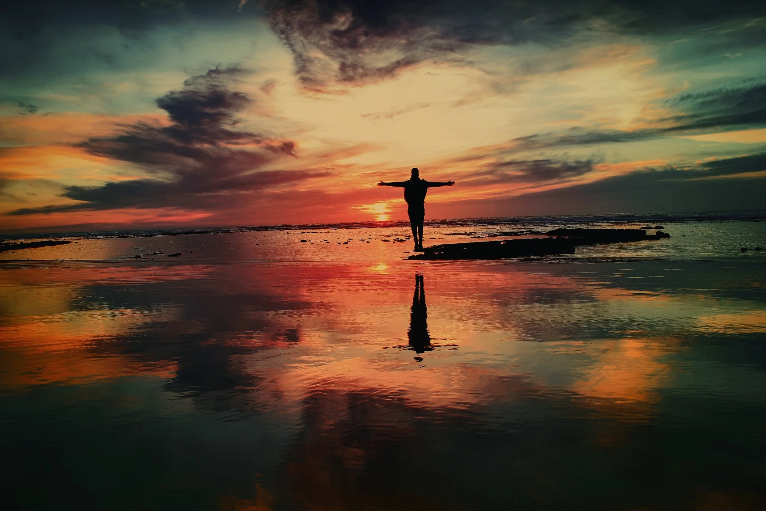 Individual with hands outstretched at sunset - Mohamed Nohassi Unsplash