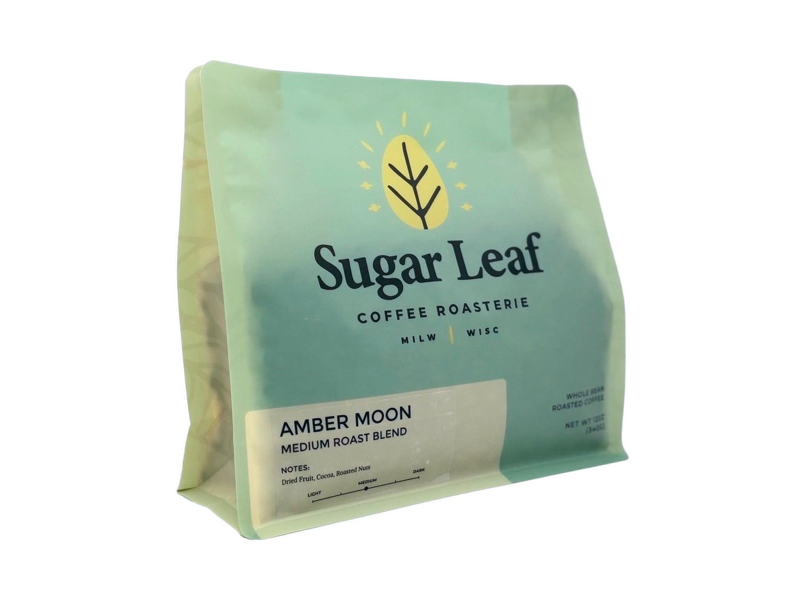 Angled view of a teal and cream 12 oz bag of Sugar Leaf Amber Moon Medium Roast Blend whole bean coffee