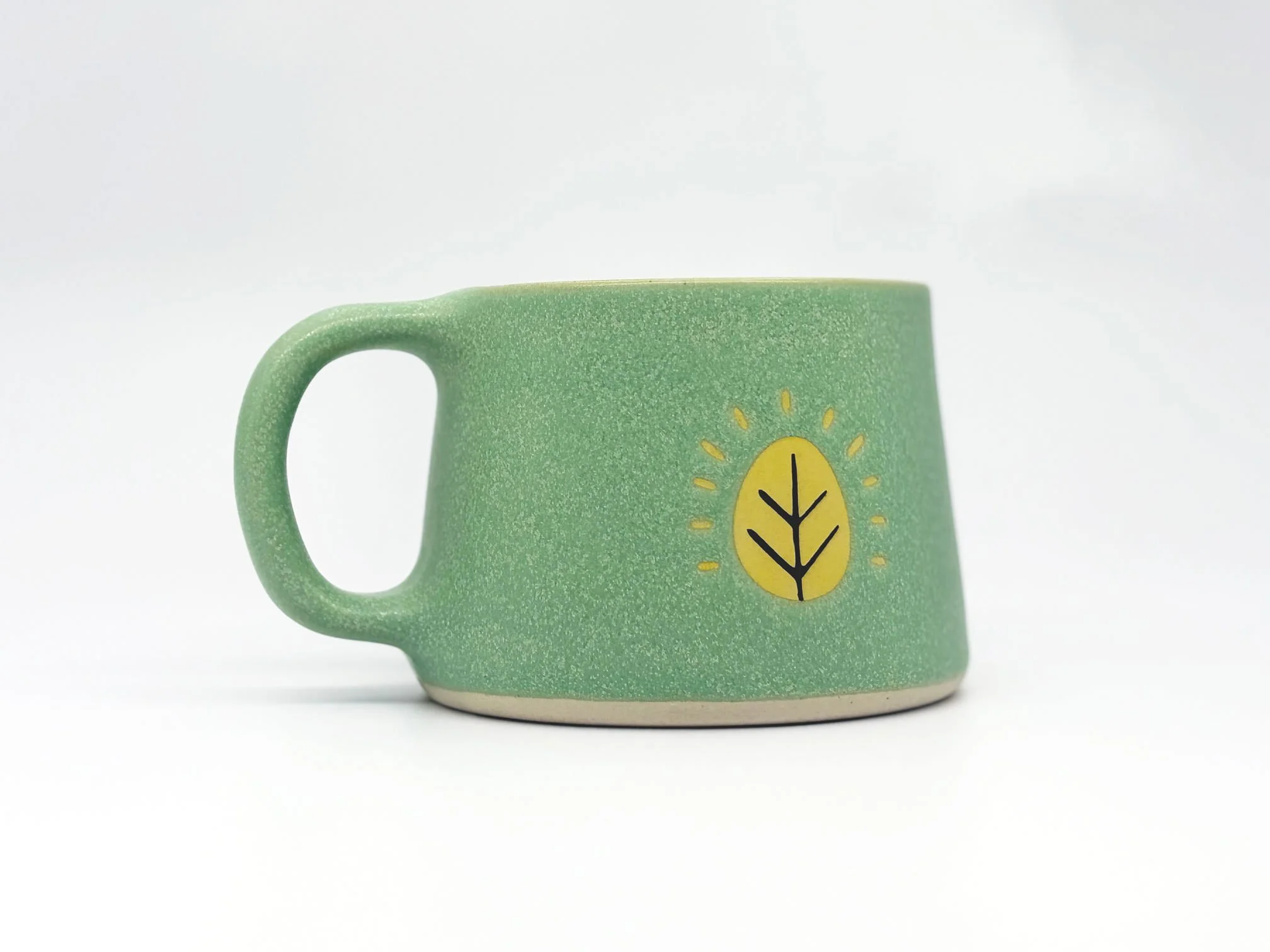 Sugar Leaf ceramic coffee mug, teal with the brand's yellow leaf mark