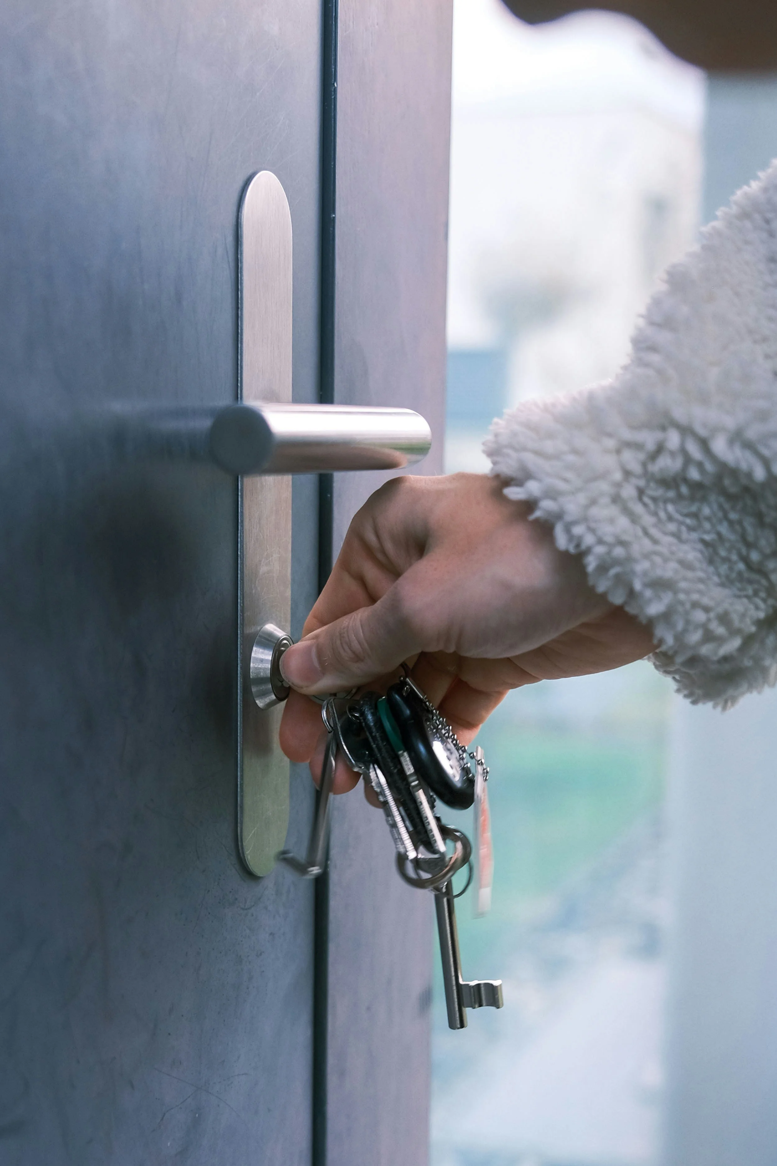 A person in a fluffy white jacket inserting a key into a lock on a gray metal locker.