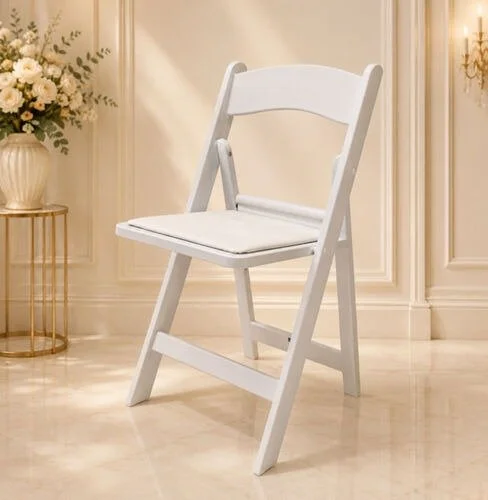 White wooden chair with a cushioned seat in a decorated room with a flower arrangement and elegant wall panels.