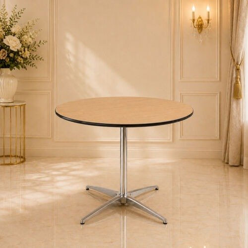 Round table with a metal base in a decorated room with beige walls, a gold side table with a flower arrangement, and a wall sconce with candles.