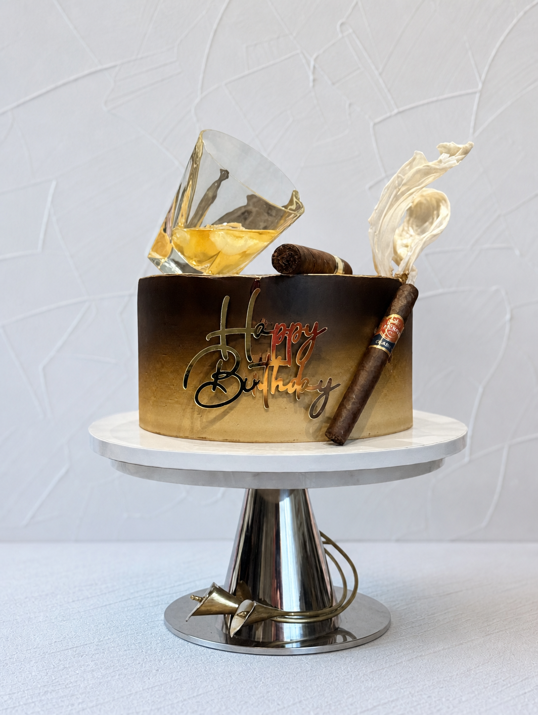 Brown and gold cake with bottle-shaped toppers.