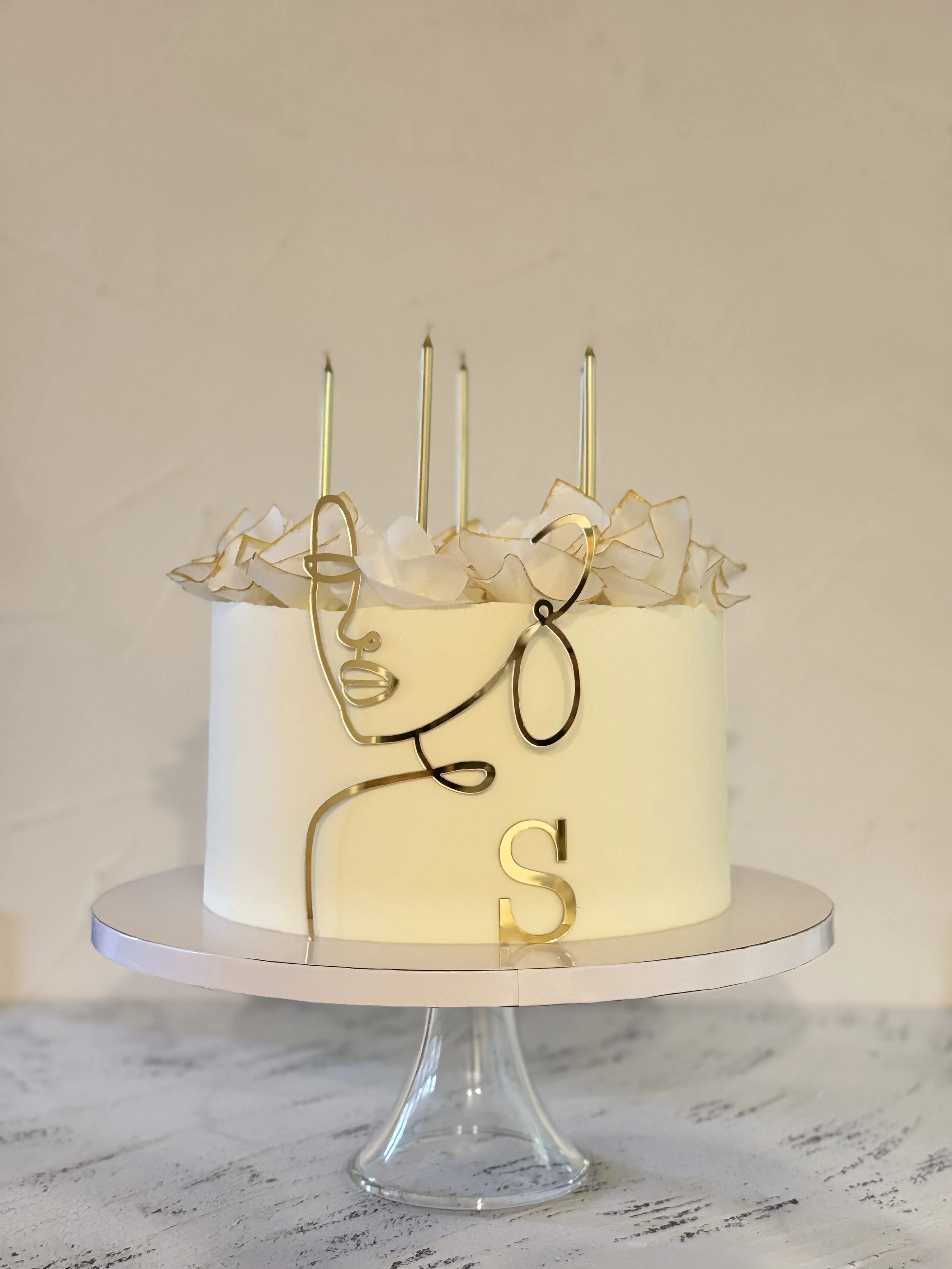 Pale yellow cake with a line-drawn face and tall candles.