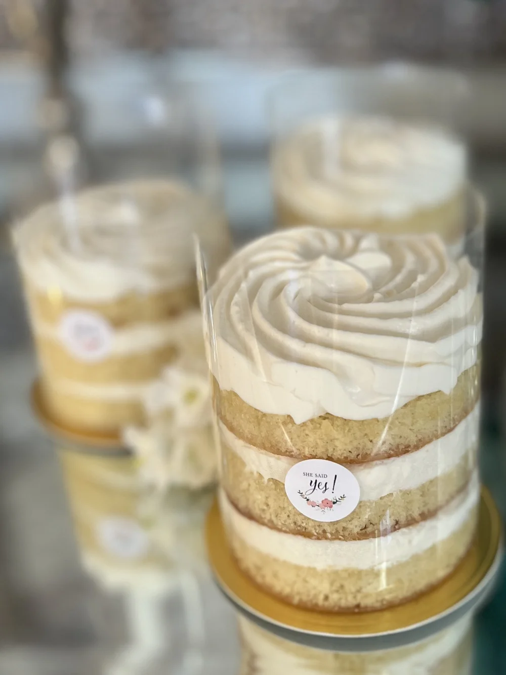 Small layered cakes with piped cream tops in clear wrapping.