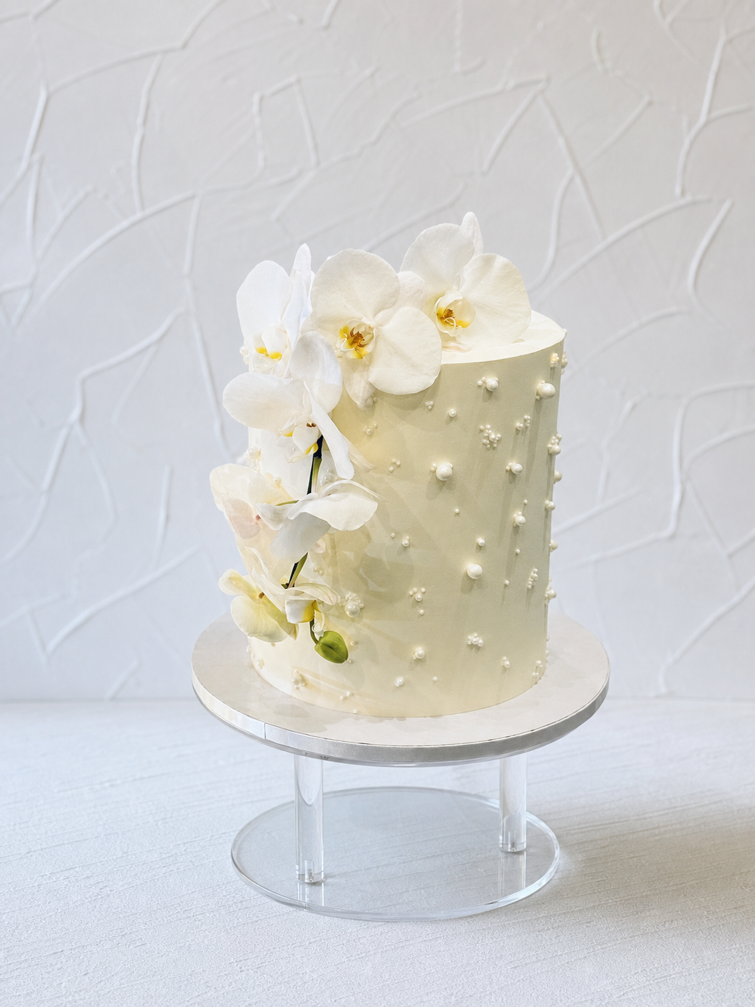 White cake with scattered pearl-like dots and white flowers.