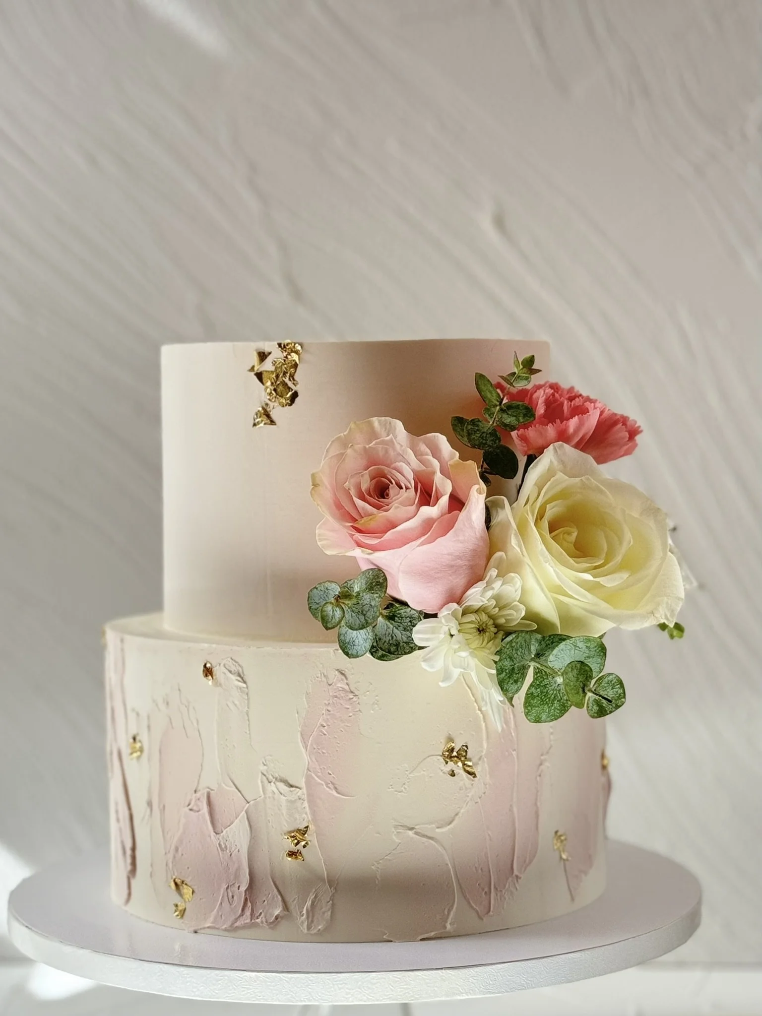 Cream cake decorated with pink and pale yellow flowers.