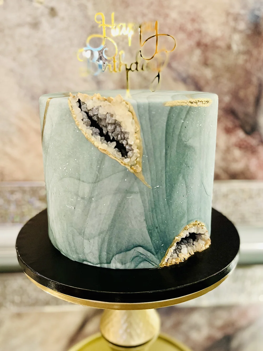 A teal cake with gold-edged geode-style decoration.