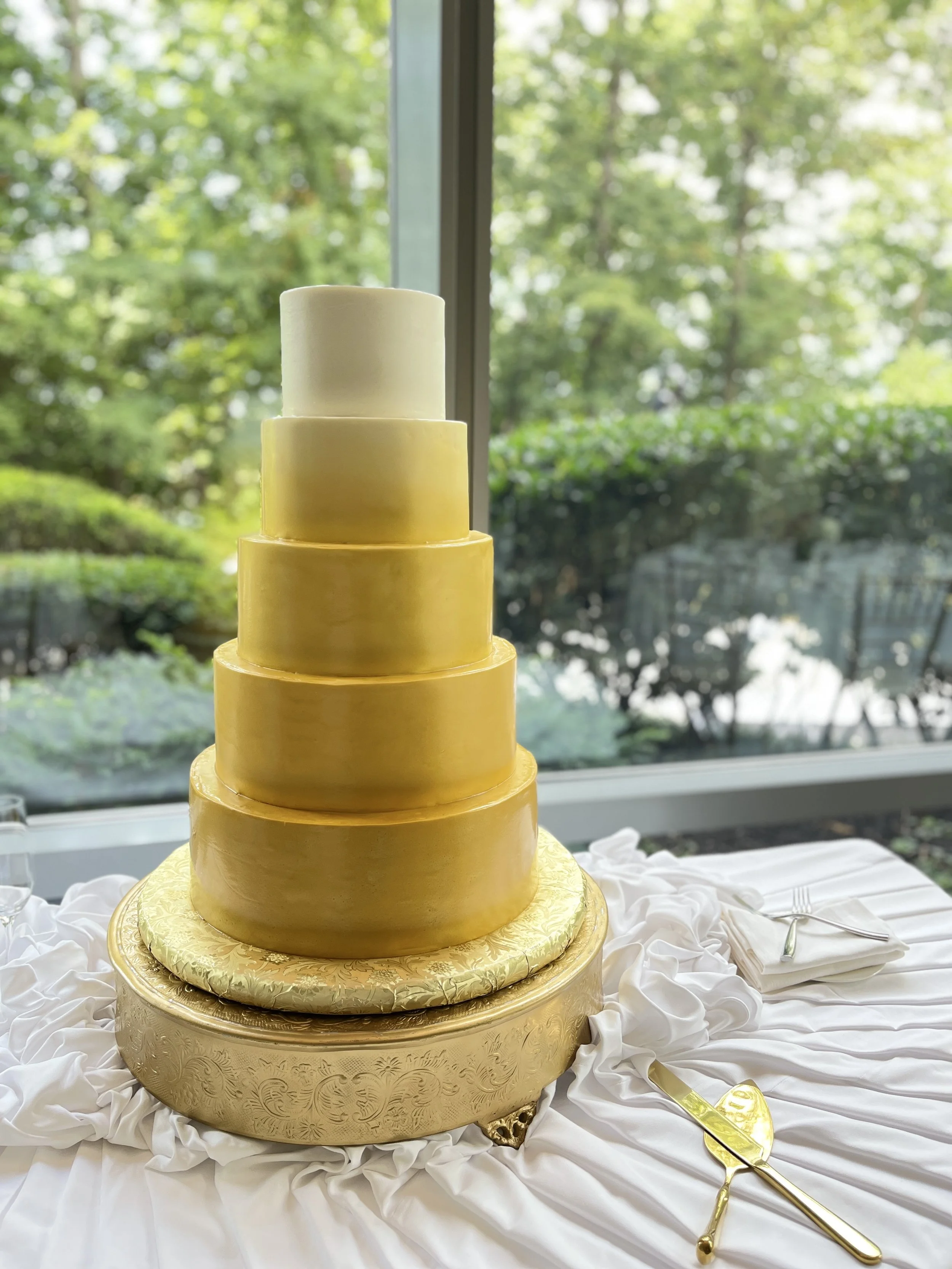 Gold tiered cake on a round gold stand.