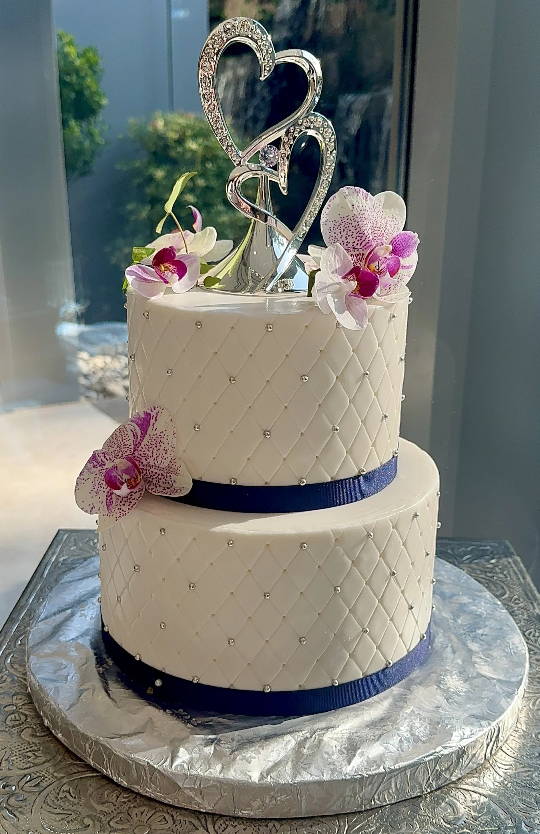 Cream tiered cake with floral decoration around a dark central band.