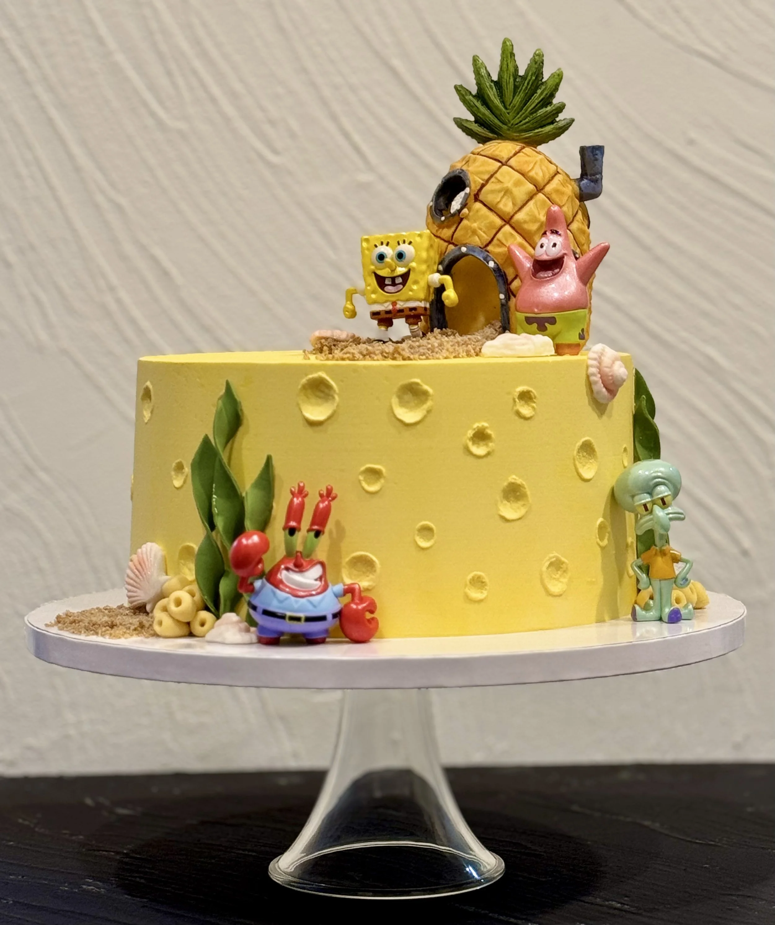 Yellow cake with cartoon character toppers and colorful decorations.