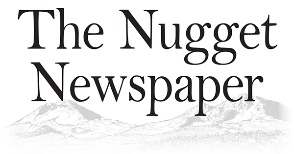 Logo for The Nugget Newspaper with a mountain landscape in the background.