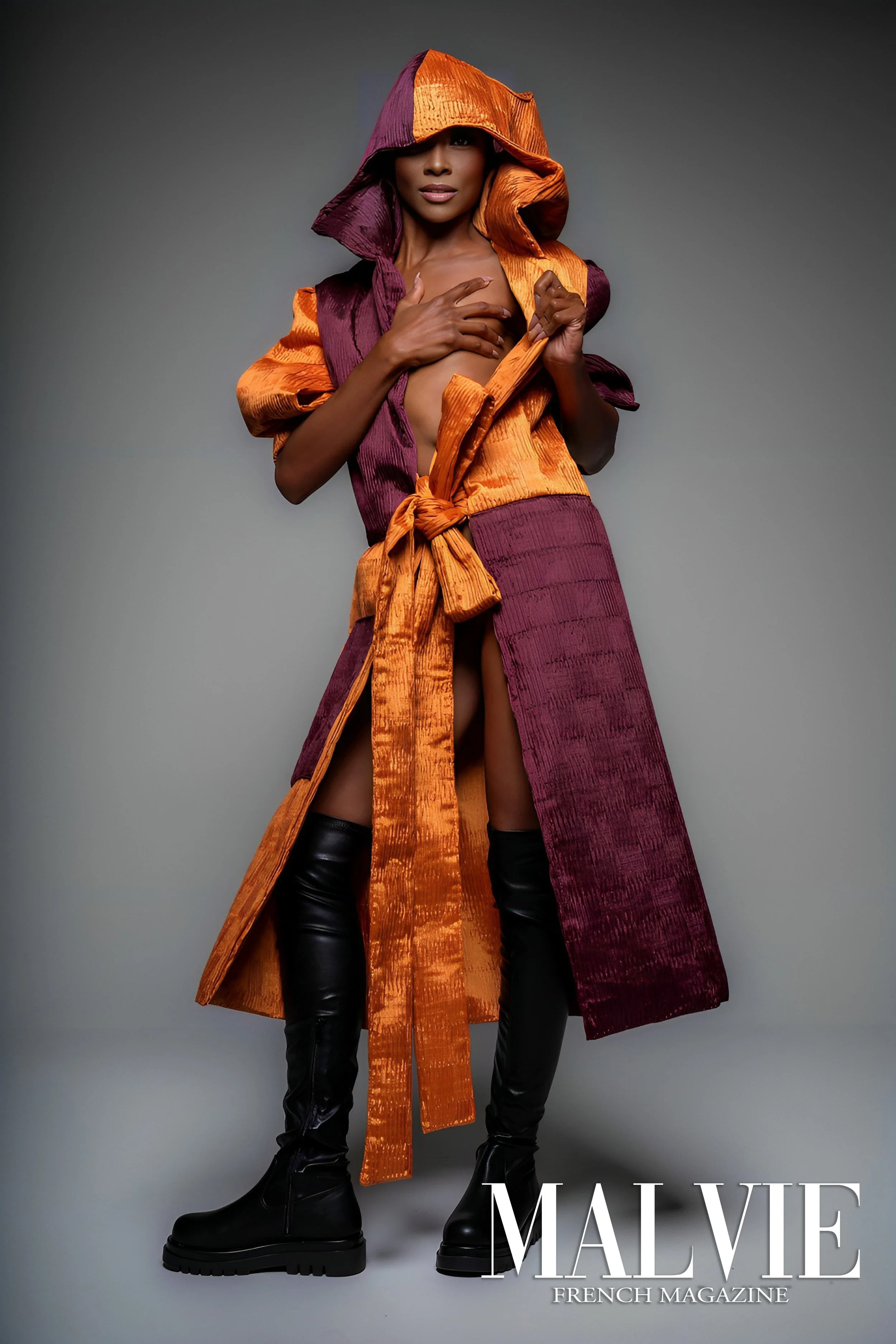 Fashion magazine cover featuring a woman in a colorful, textured coat with a hood, wearing black thigh-high boots, posed against a gray background, with the text 'MALVIE FRENCH MAGAZINE' at the bottom right.