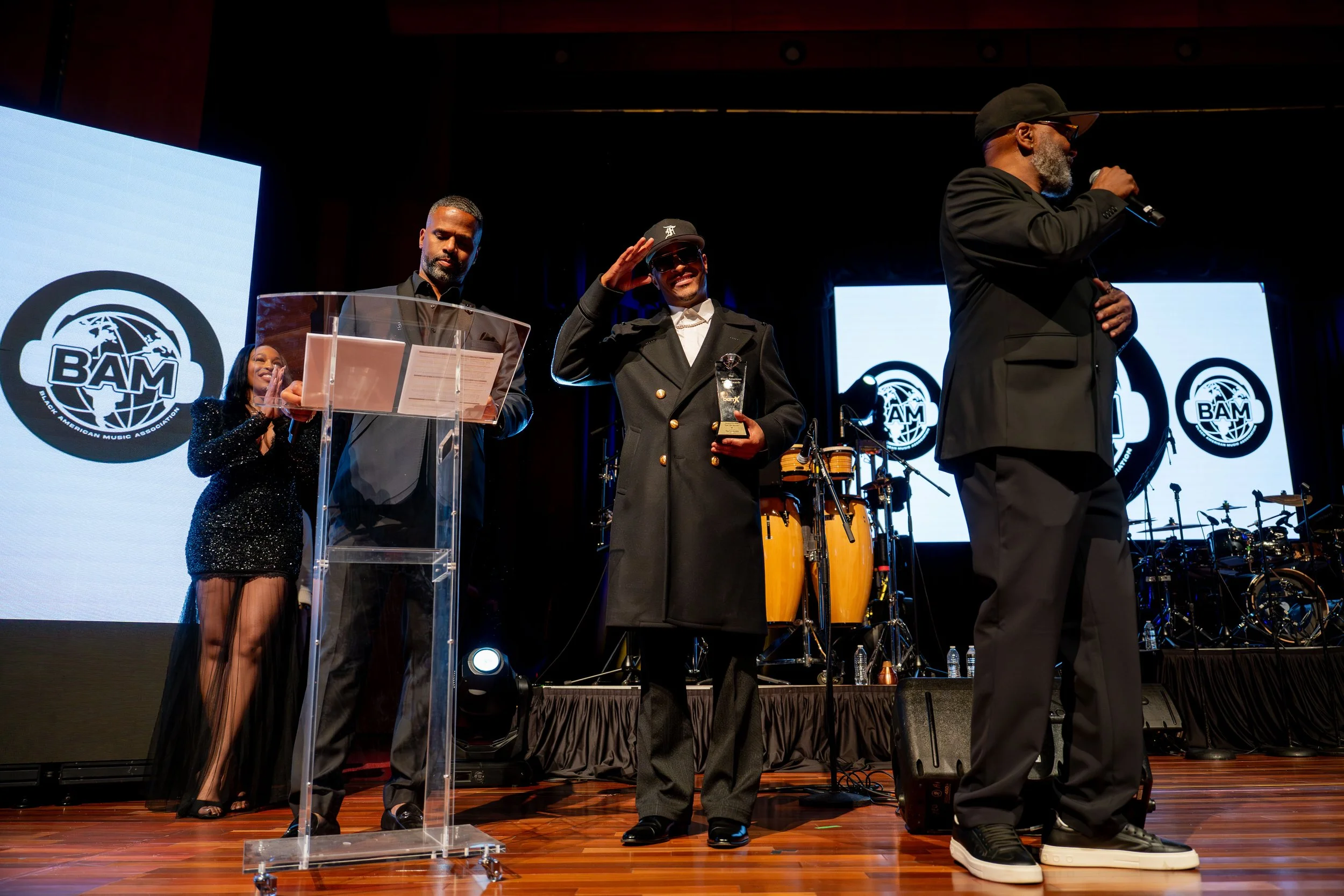 People on stage during an award ceremony with the BAM logo displayed on screens behind them.