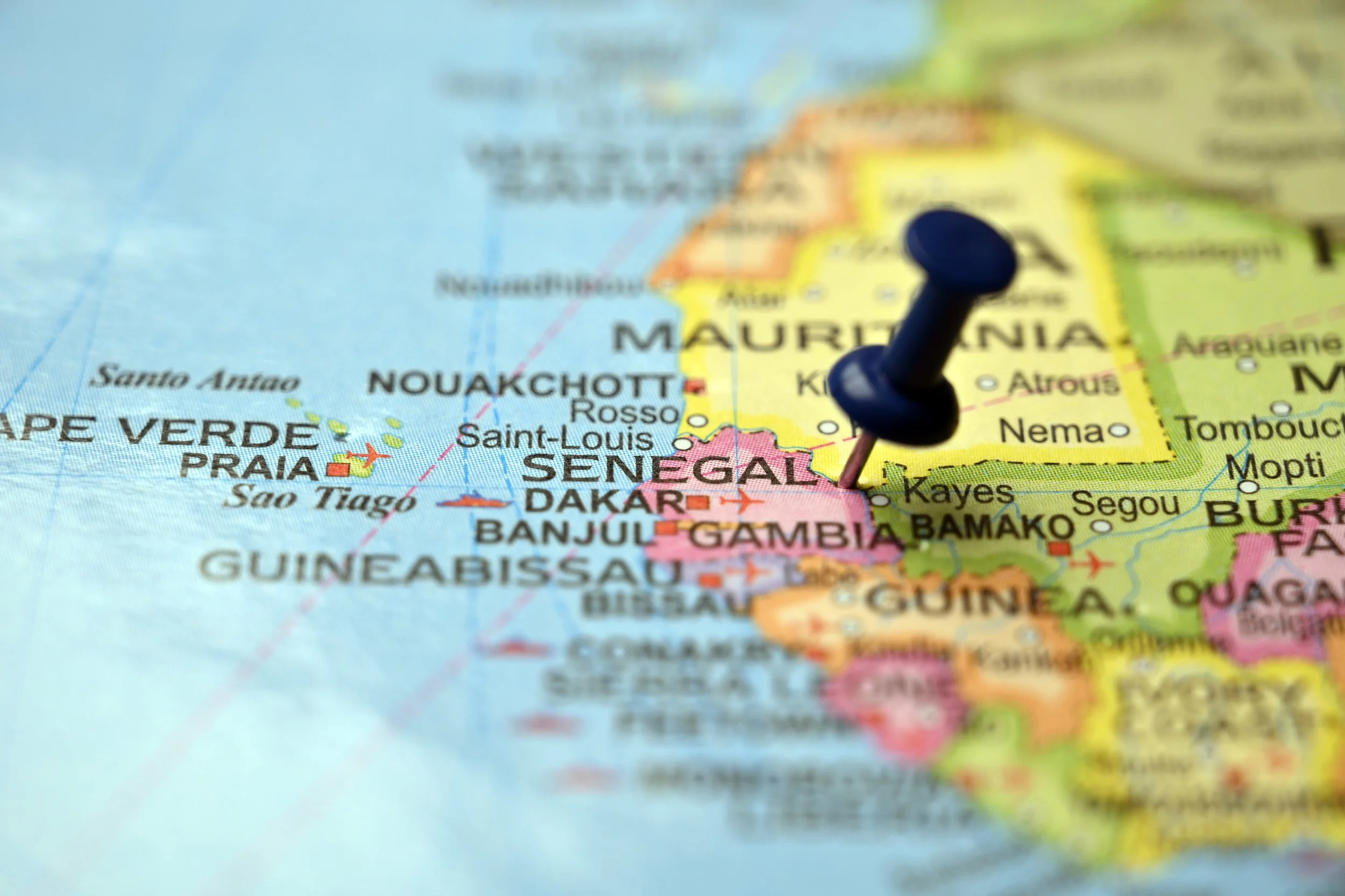 Close-up of a world map with a blue pushpin marking a location in Senegal.