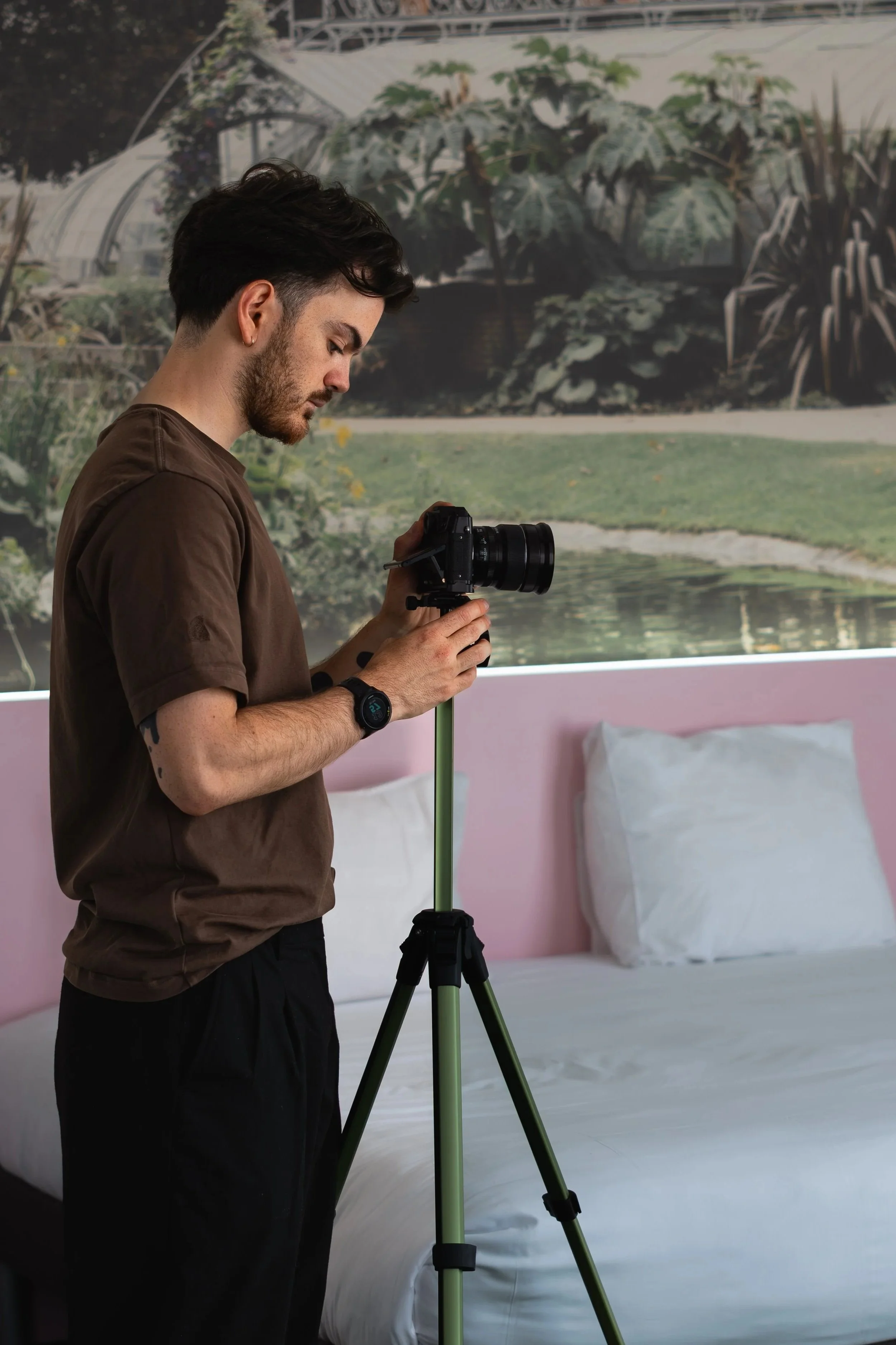 Jeune homme réglant un appareil photo sur un trépied dans une chambre d'hôtel