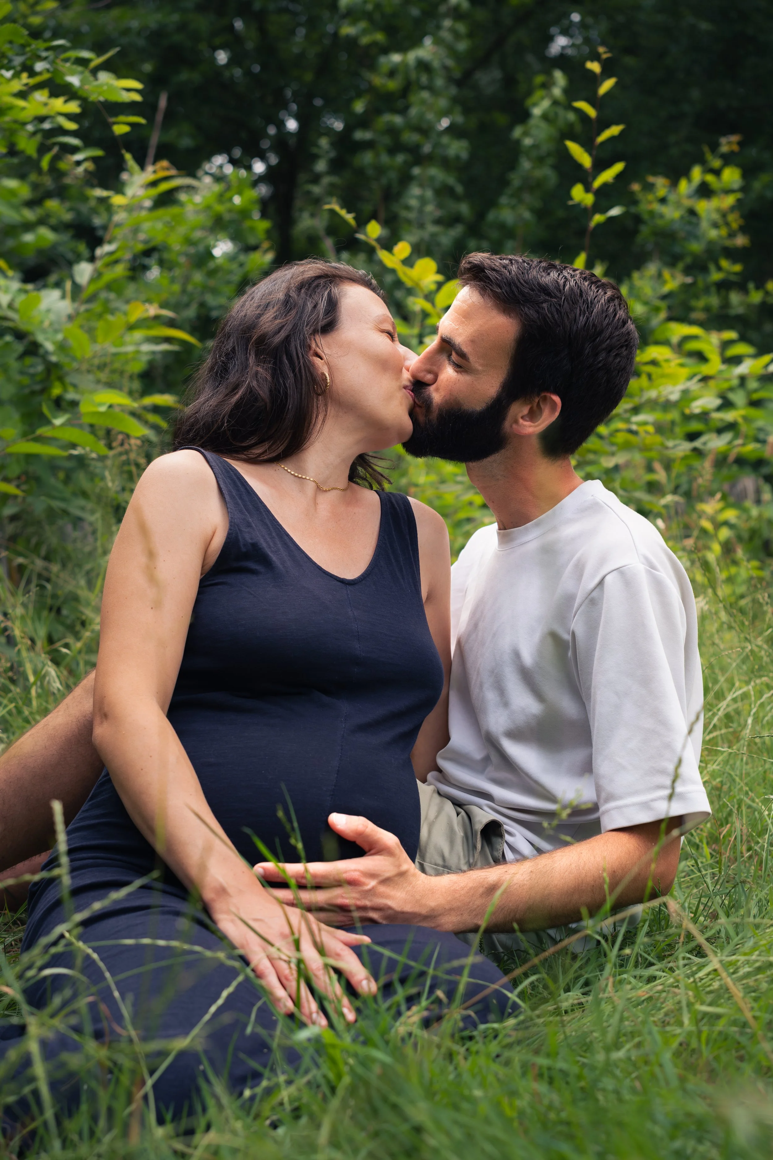 Un couple s'embrasse dans un paysage naturel verdoyant.